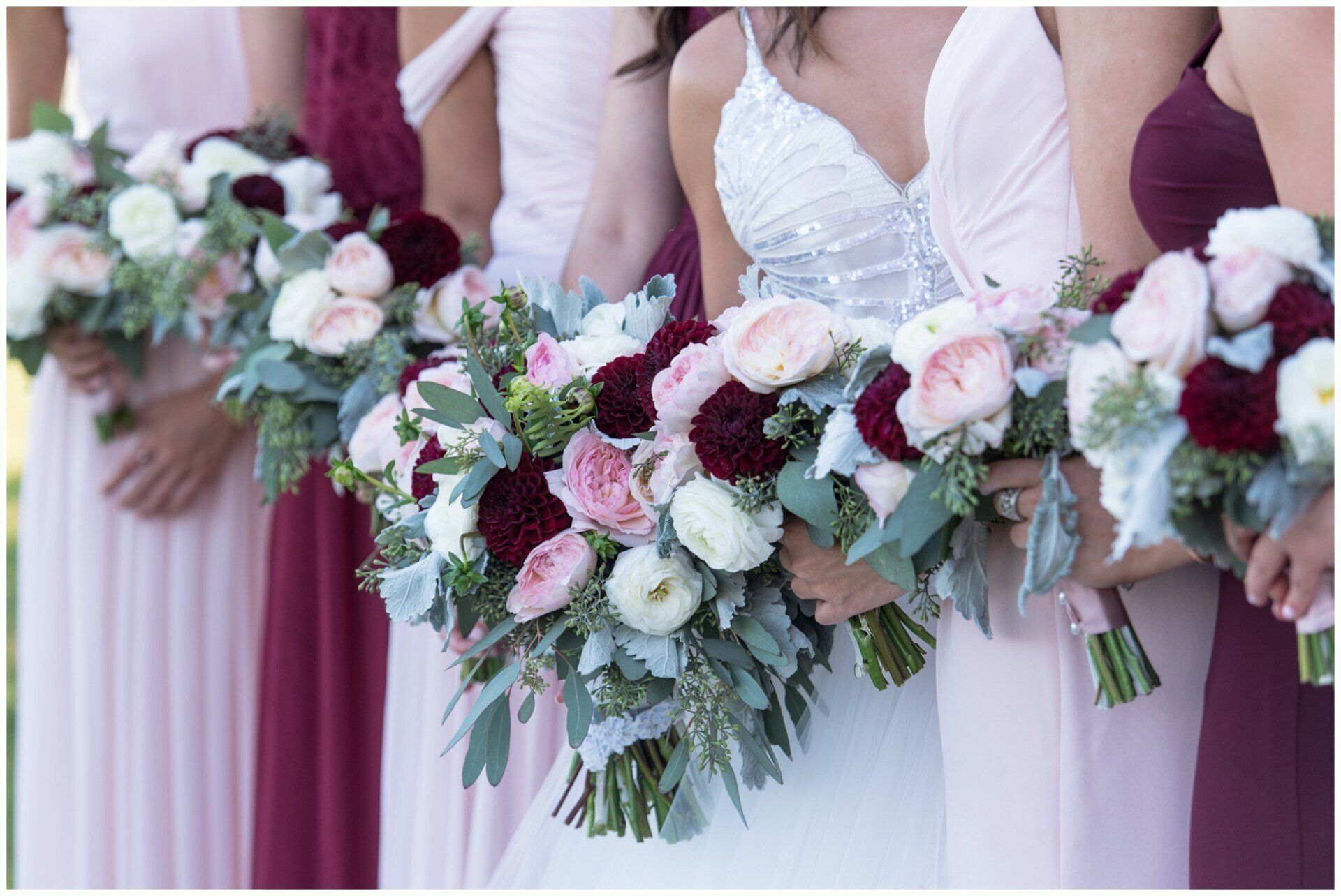 Bridesmaids in mauve dresses holding white and pink wedding bouquets