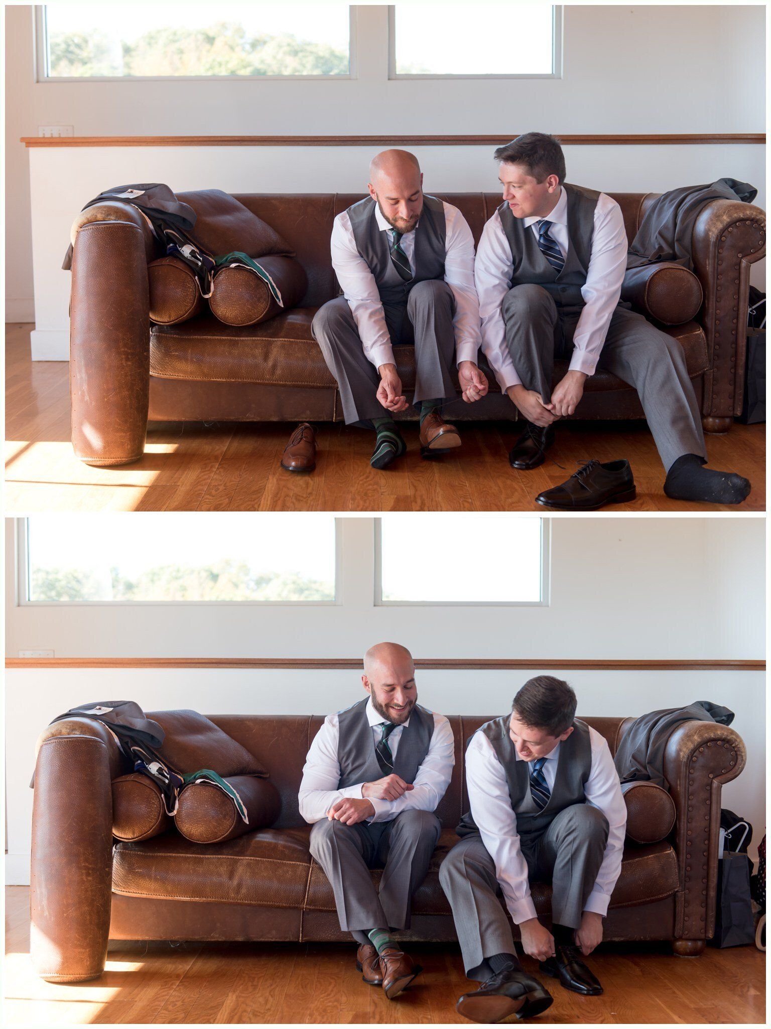 Two men in gray vests sit on a brown leather couch, leaning forward and looking down at their shoes.