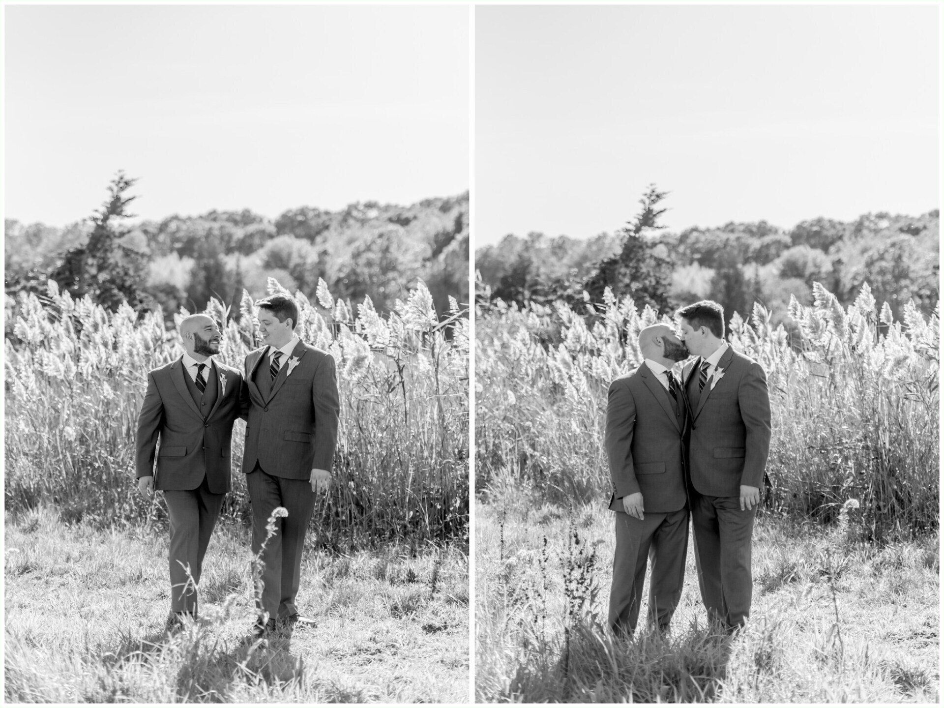 Two people in dark suits standing together in a grassy field with trees behind them, in black and white.