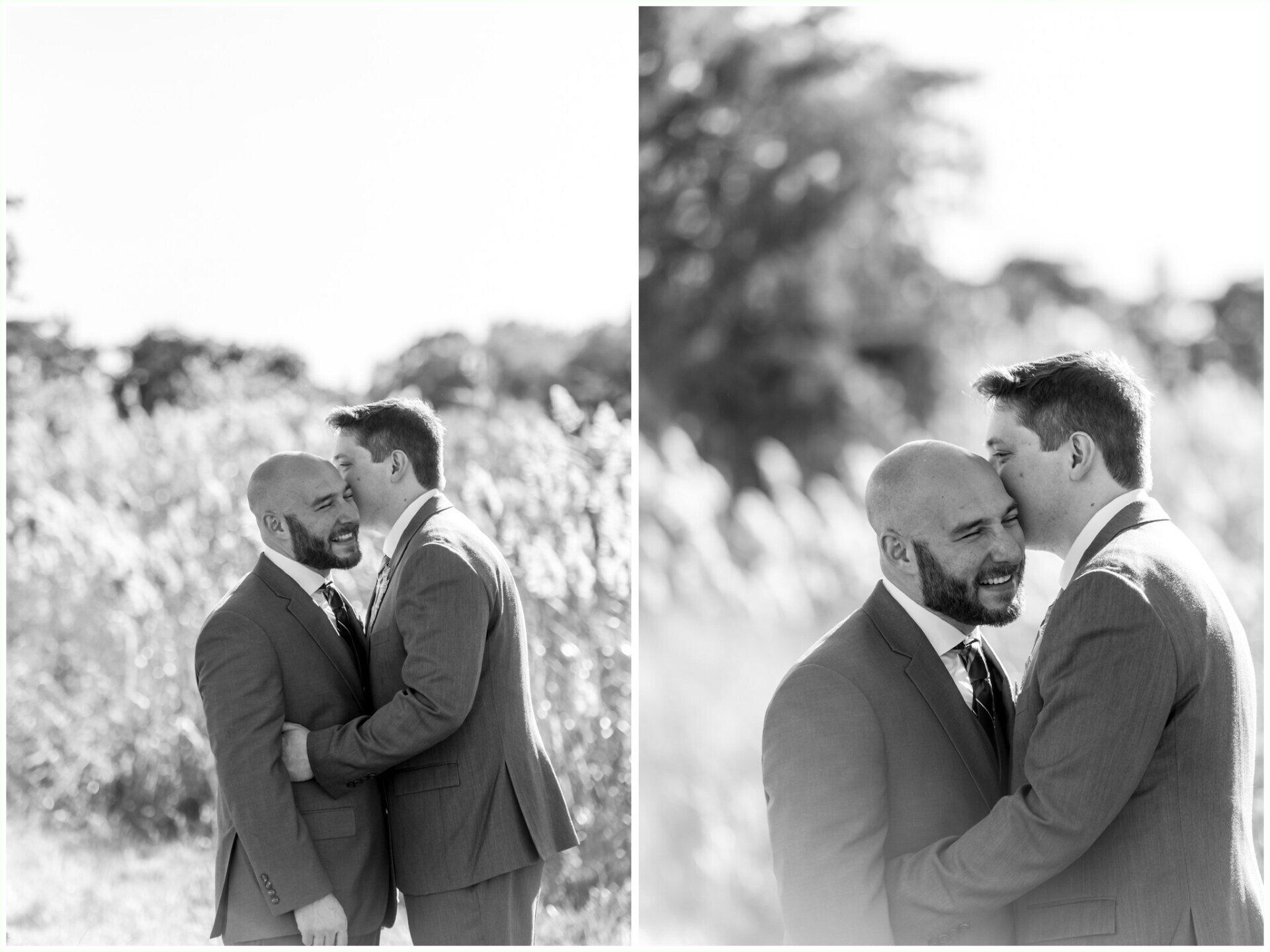 Two men in suits embrace outdoors, standing close in a grassy field.