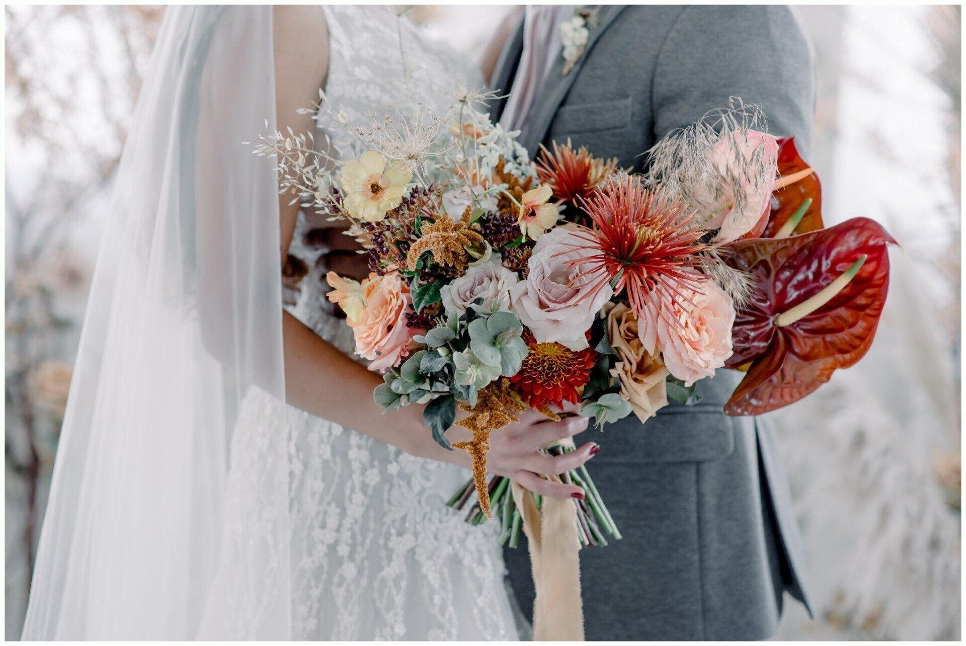 Bride holding a colorful autumn bouquet with dried flowers and red leaves