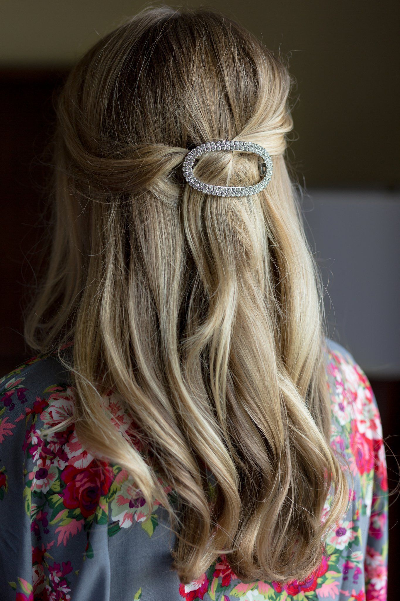 Back view of a person with long blonde hair clipped half up, wearing a floral top.