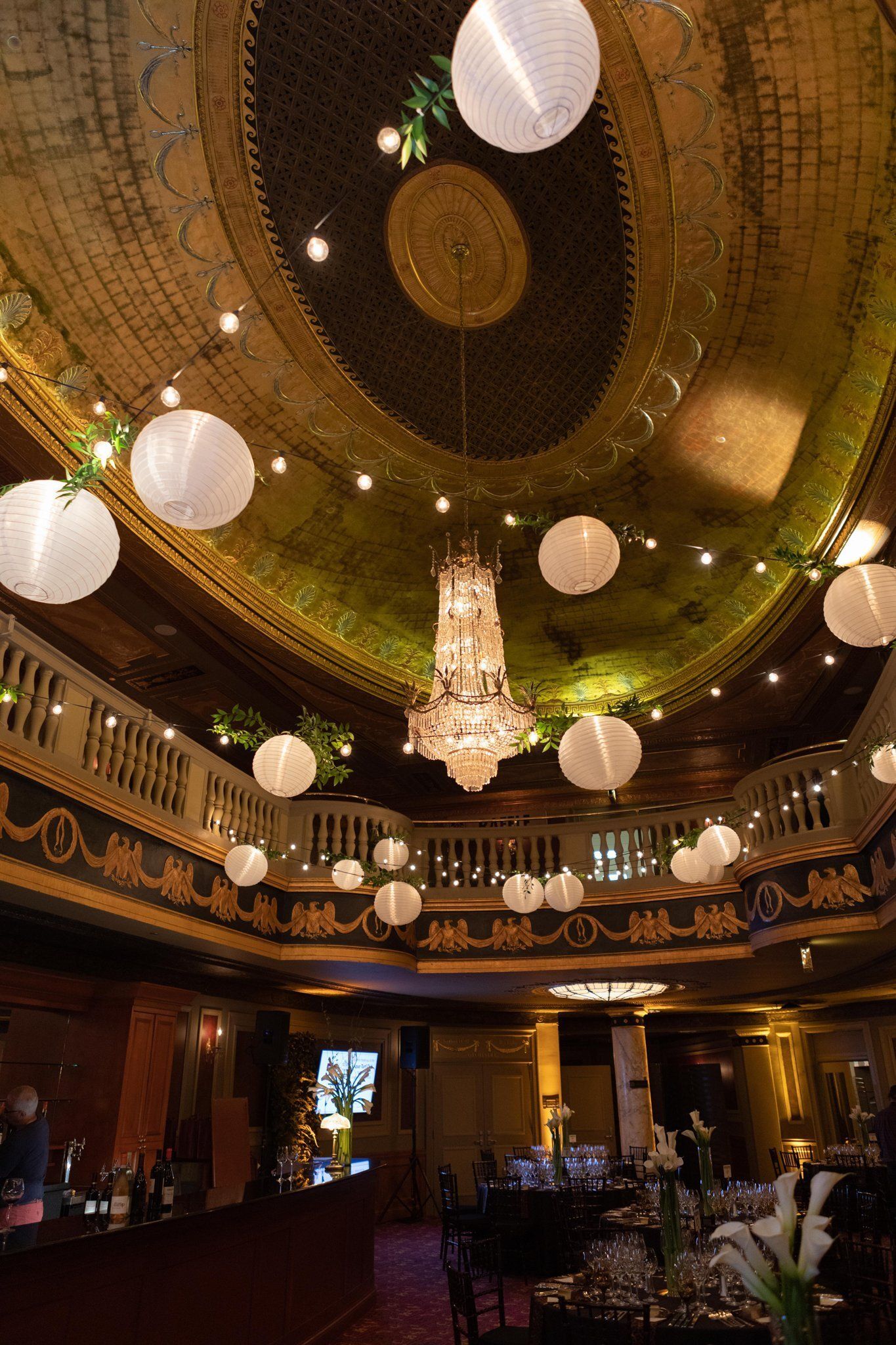 Ornate theater or ballroom interior with a gold ceiling and hanging round lanterns, warmly lit below
