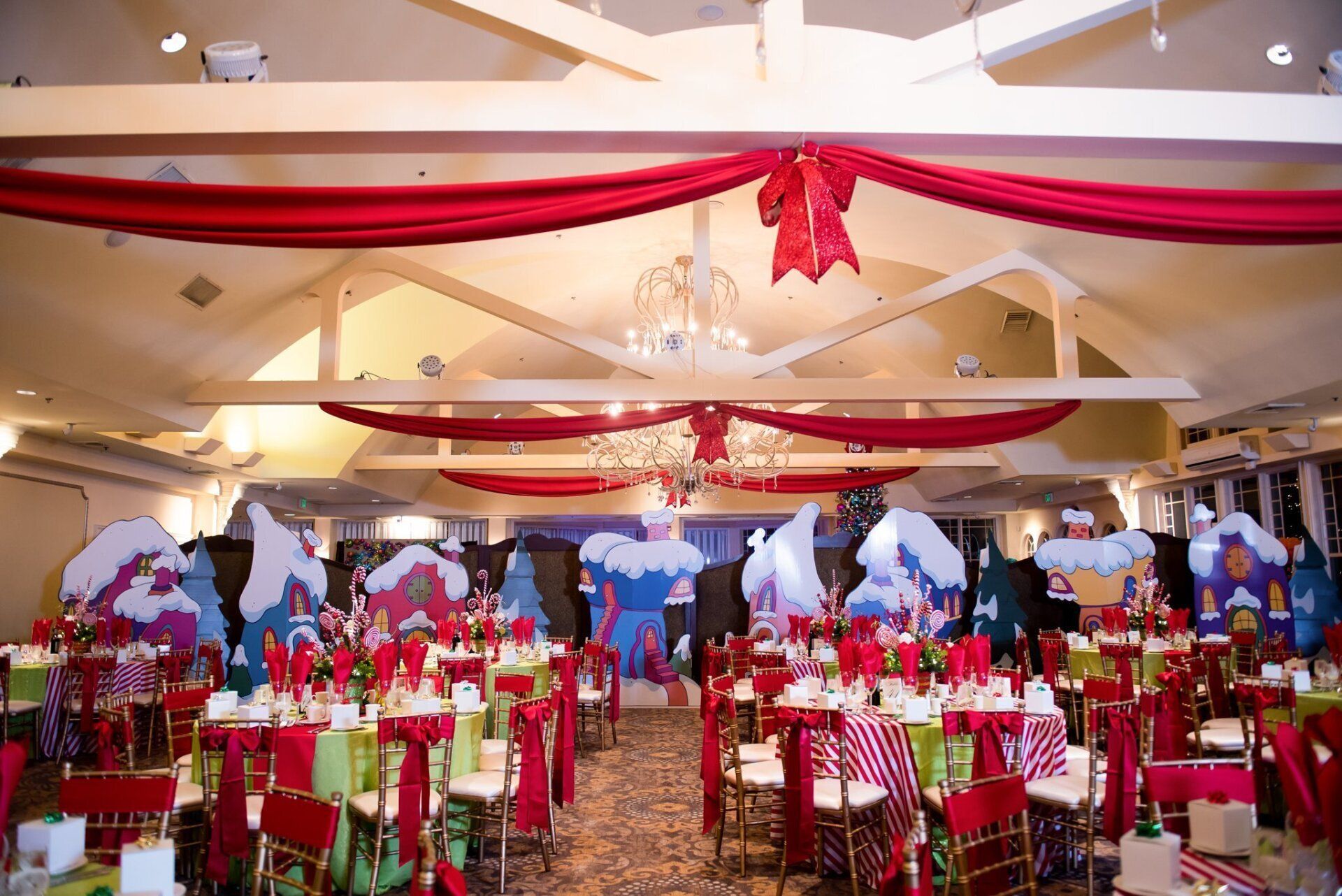 Decorated banquet hall with red and white drapery, gold chairs, and set tables for a formal event