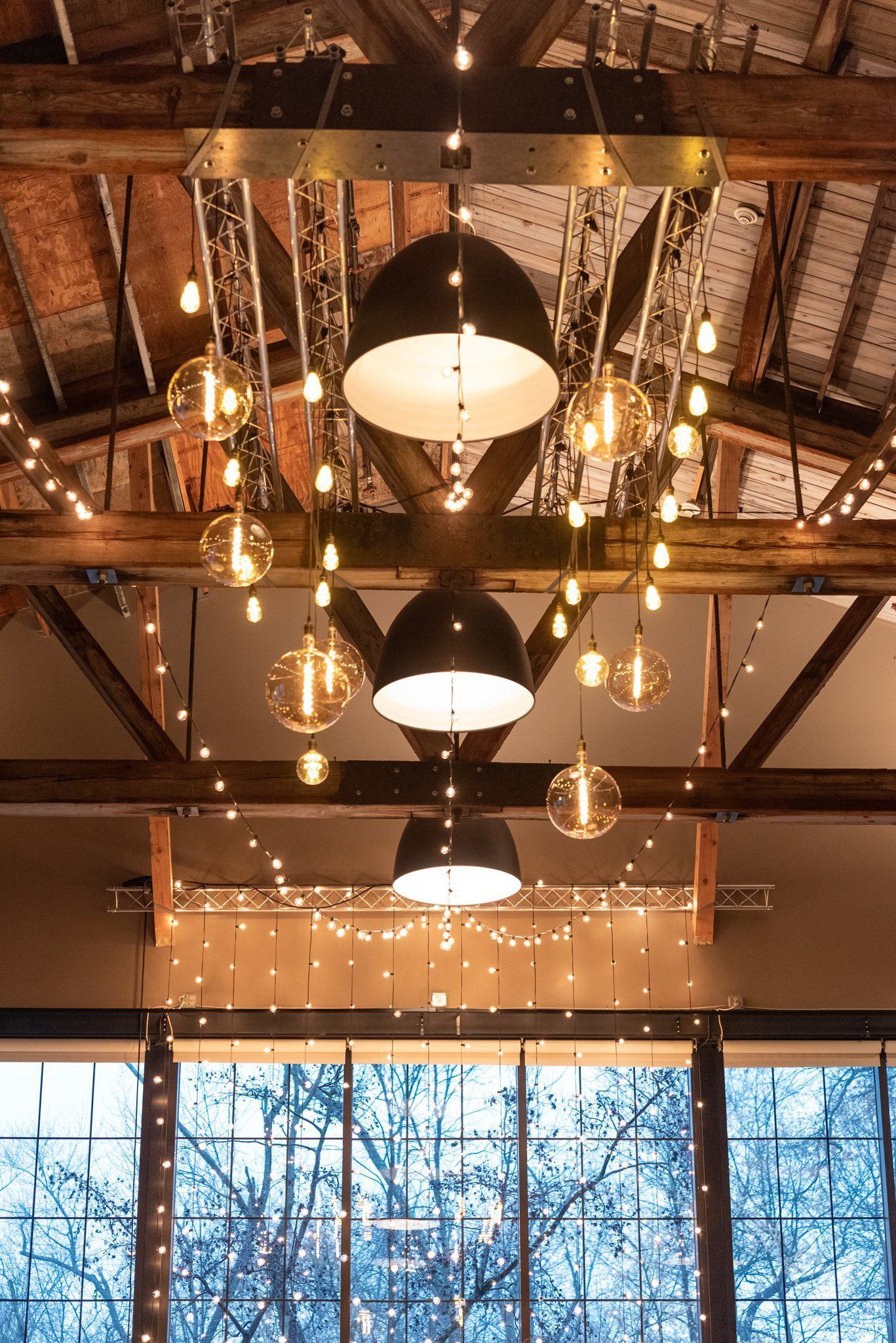 Warmly lit chandelier ceiling over large windows showing snowy trees outside