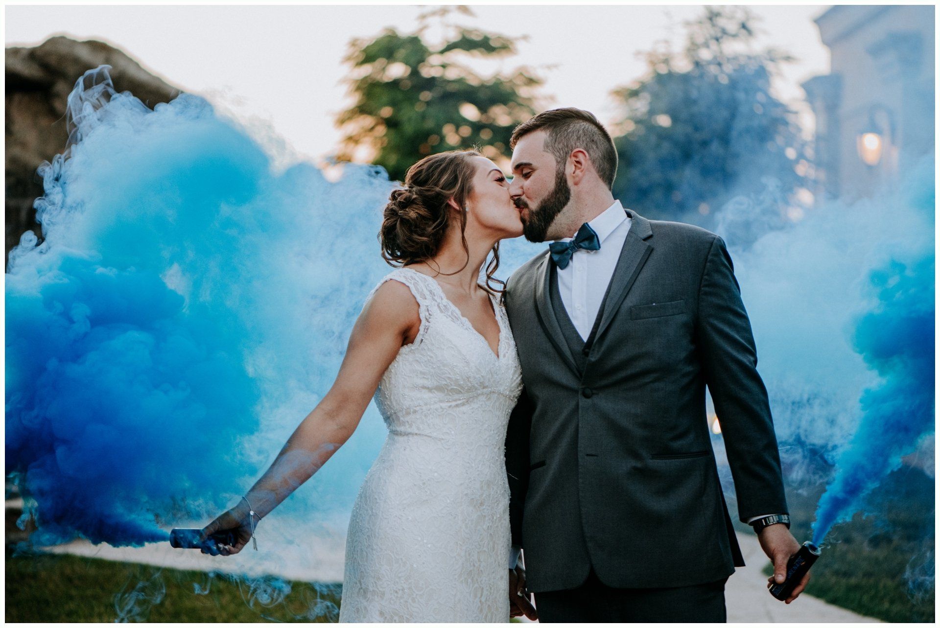 Wedding couple kissing amid blue smoke outdoors