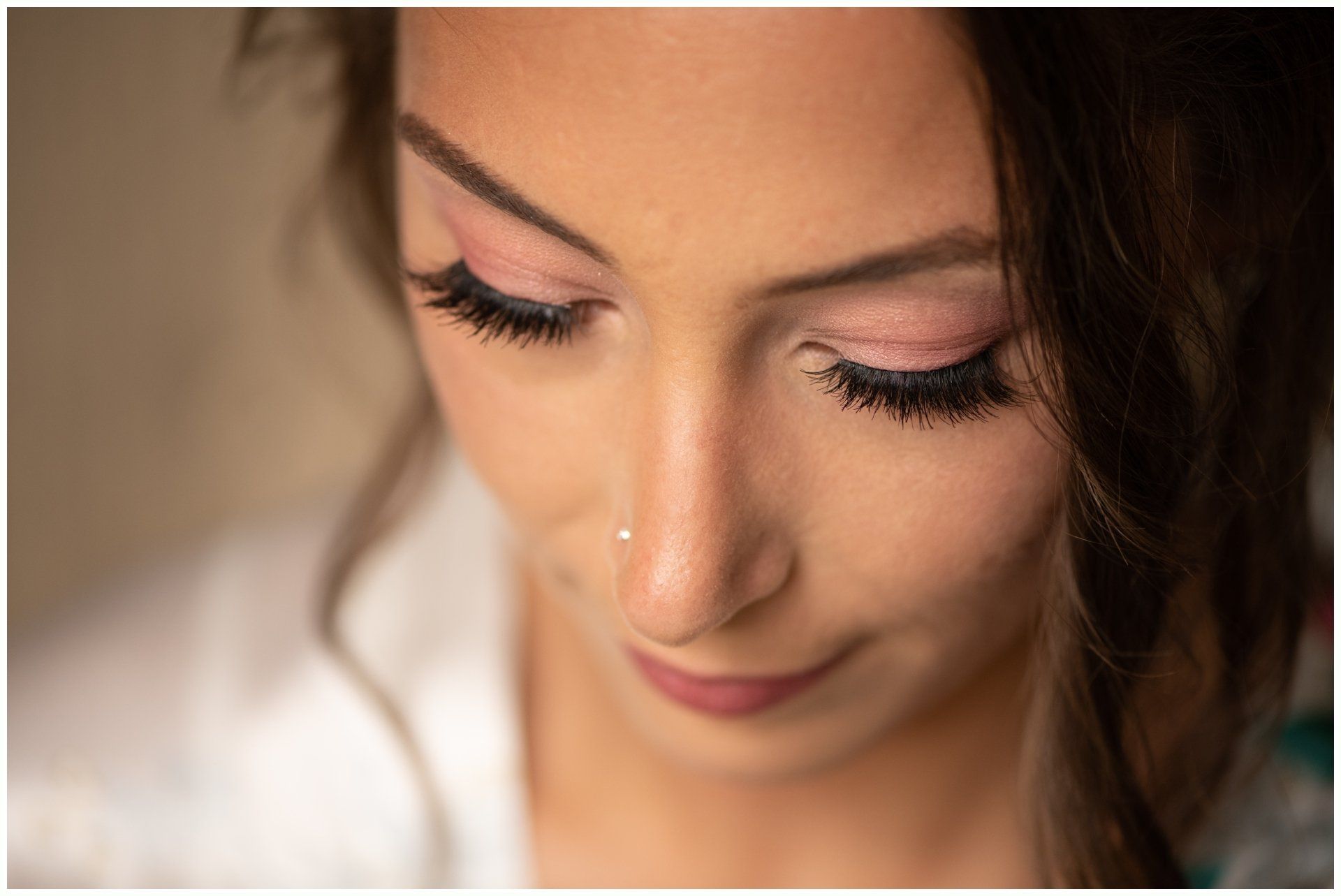 Close-up of a woman looking down with soft makeup and pink eyeshadow