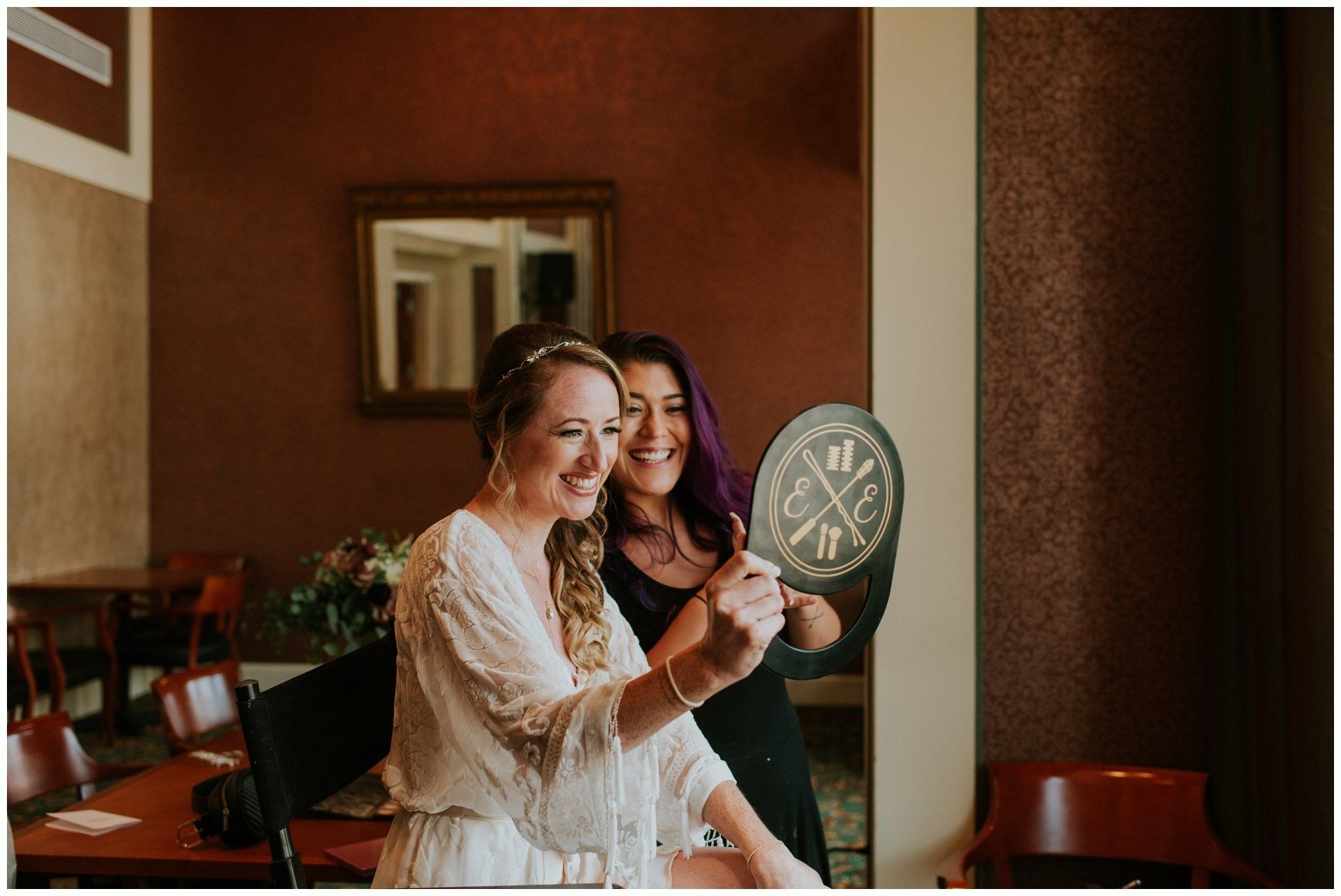 Two women smiling and holding a round plaque in a warmly lit room