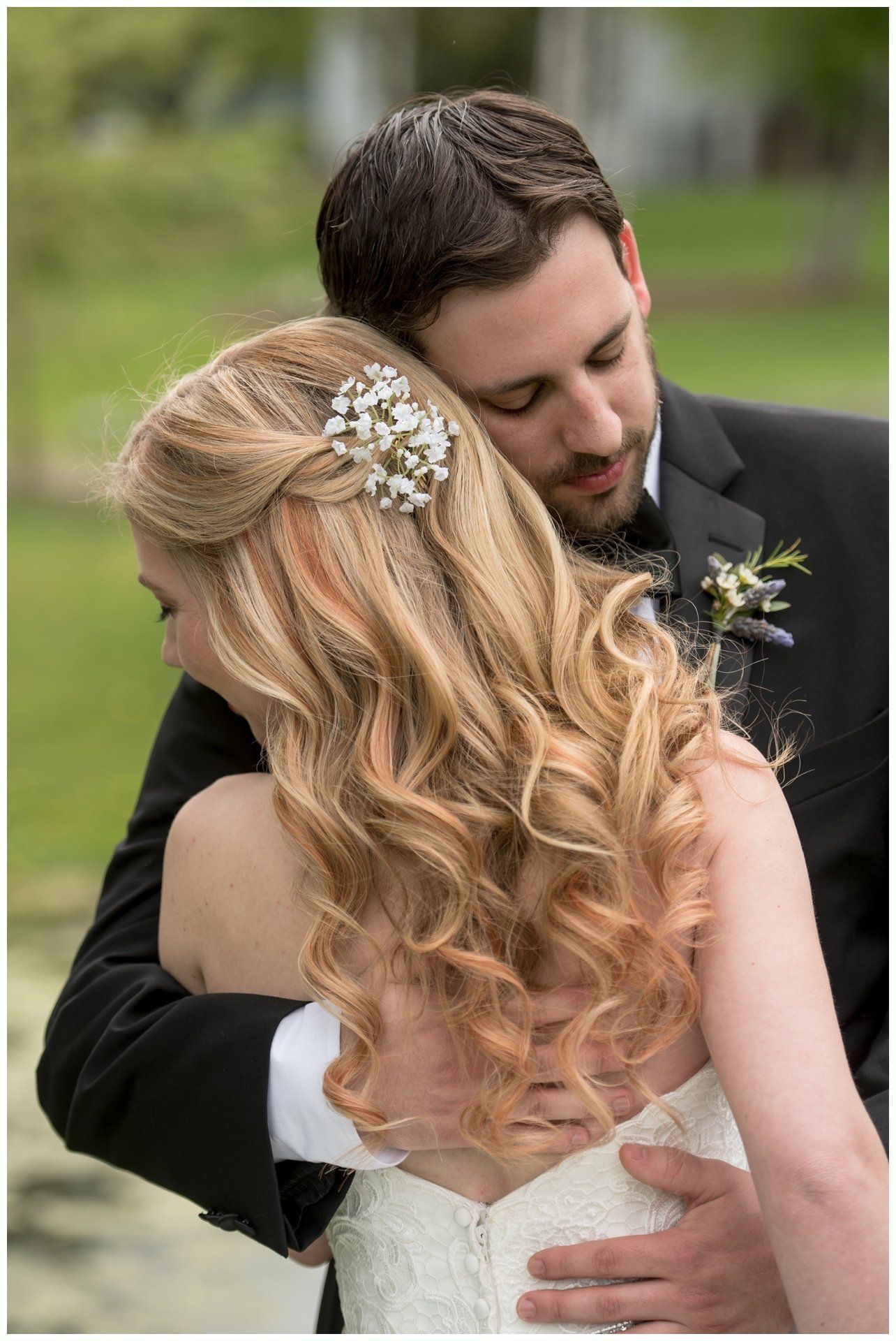 Bride and groom embracing outdoors, with the groom kissing her forehead