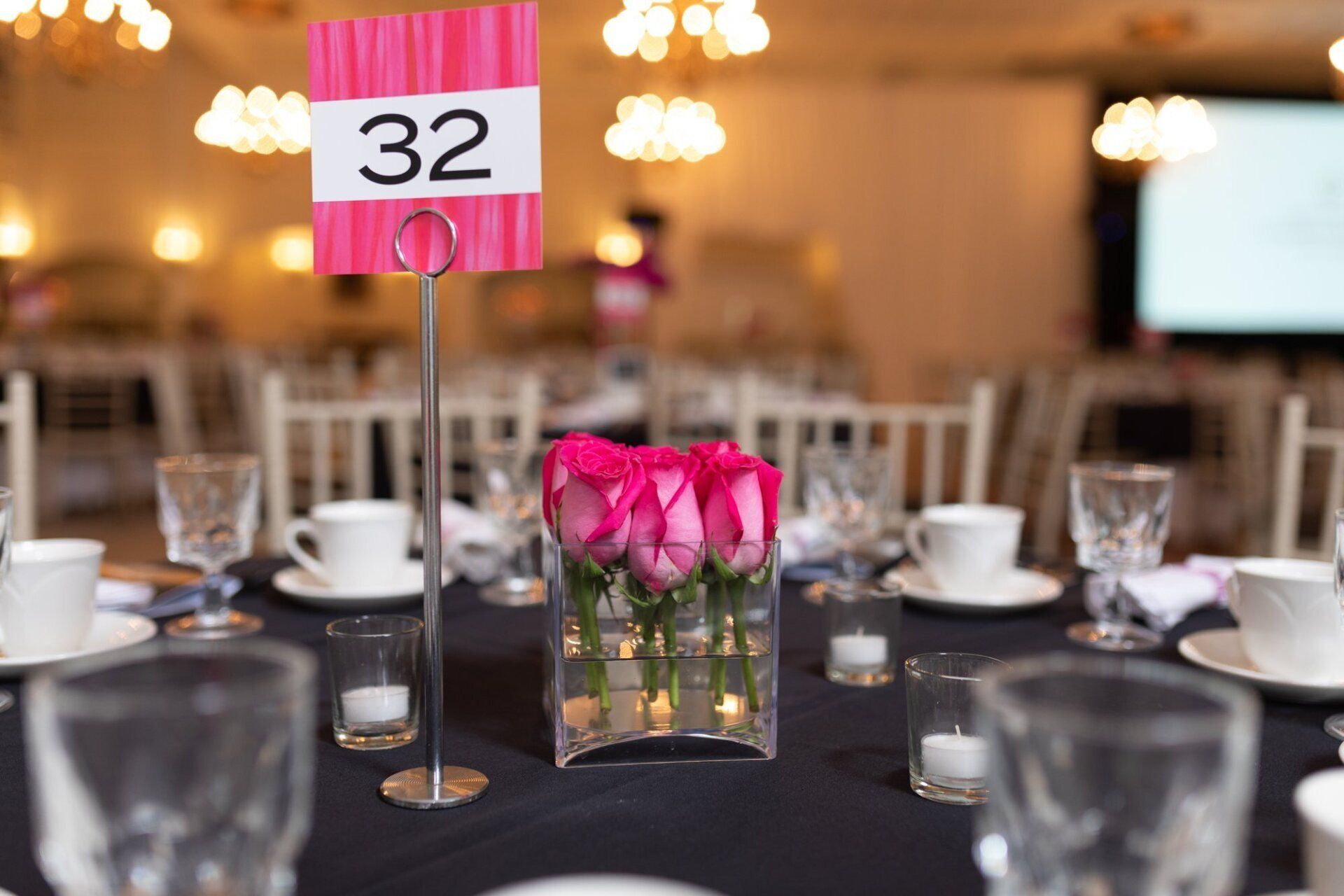 Table centerpiece with pink roses and a “32” table number at a banquet reception