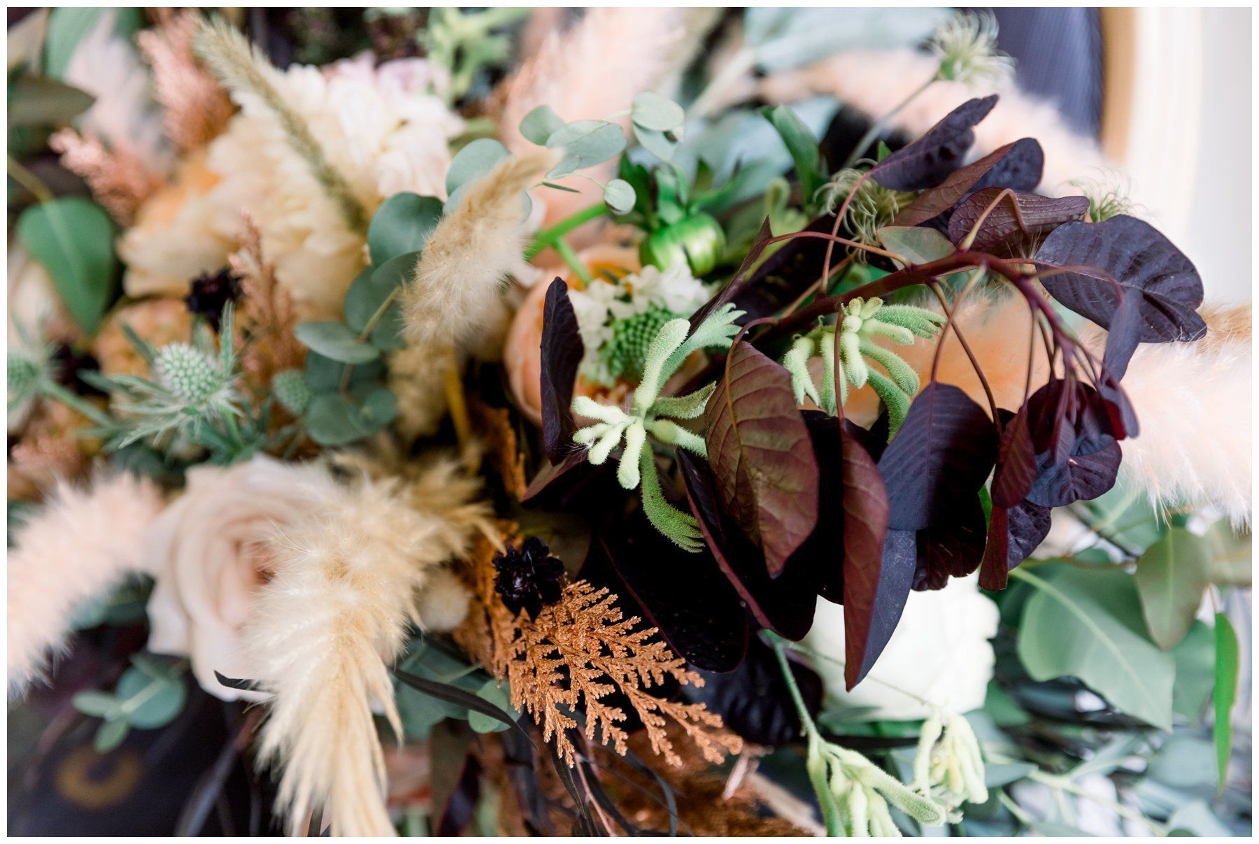 Muted floral arrangement with cream, green, and burgundy dried flowers and foliage
