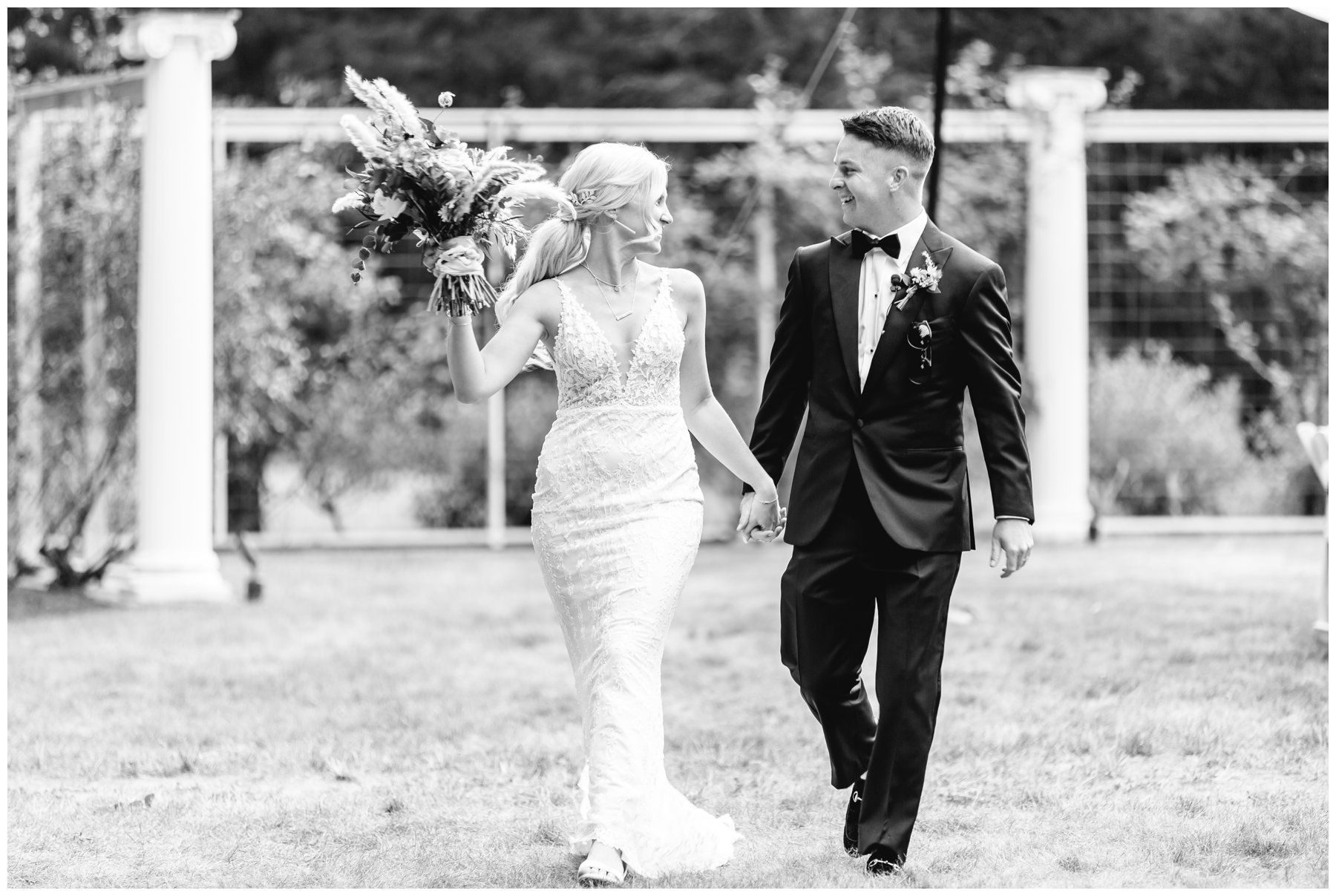 Bride and groom walking together outdoors, bride holding a bouquet in a white dress