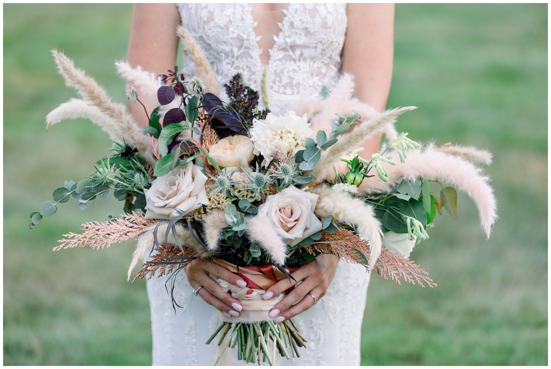 Bride holding a soft pastel wedding bouquet with roses and greenery in a white dress outdoors