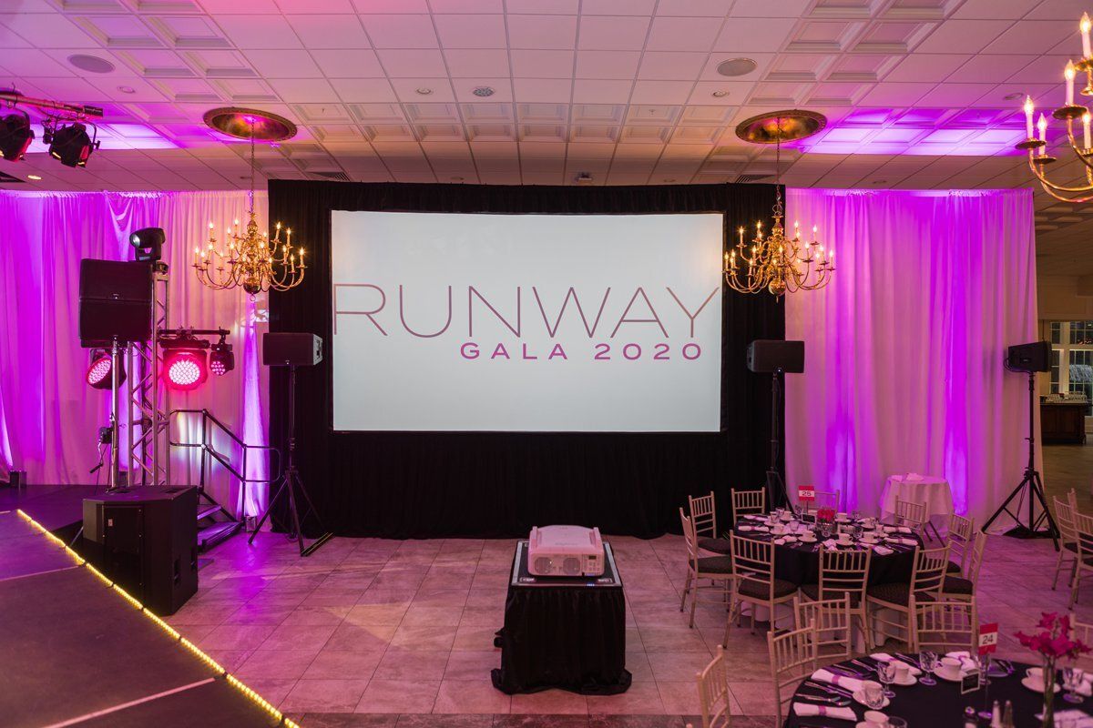 Runway Gala 2020 stage with pink lighting and dining tables in a banquet hall
