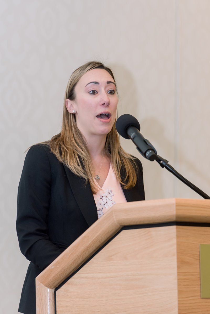 Woman speaking at a podium with a microphone during a presentation