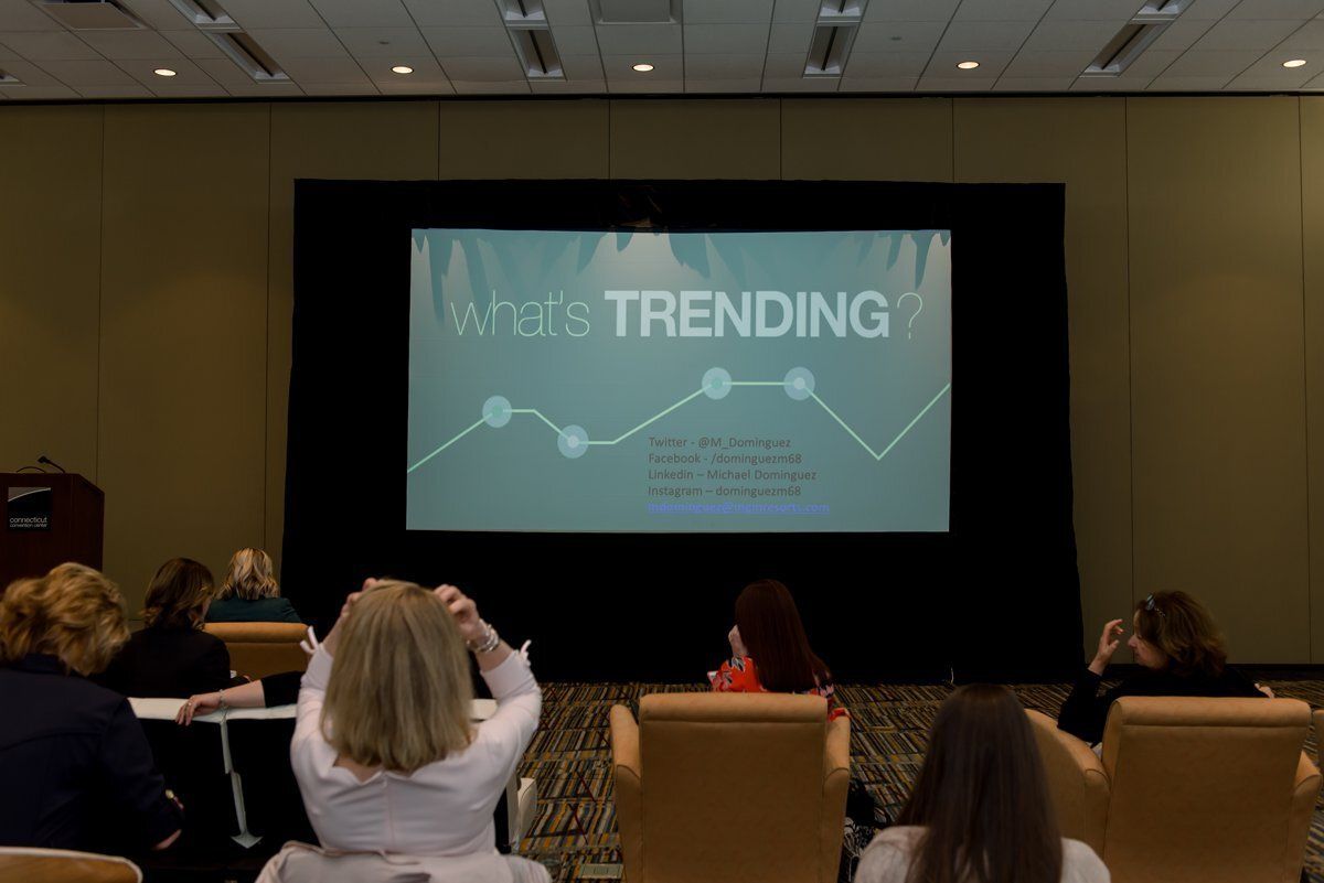 Audience watching a presentation on “Trending” at a conference room screen