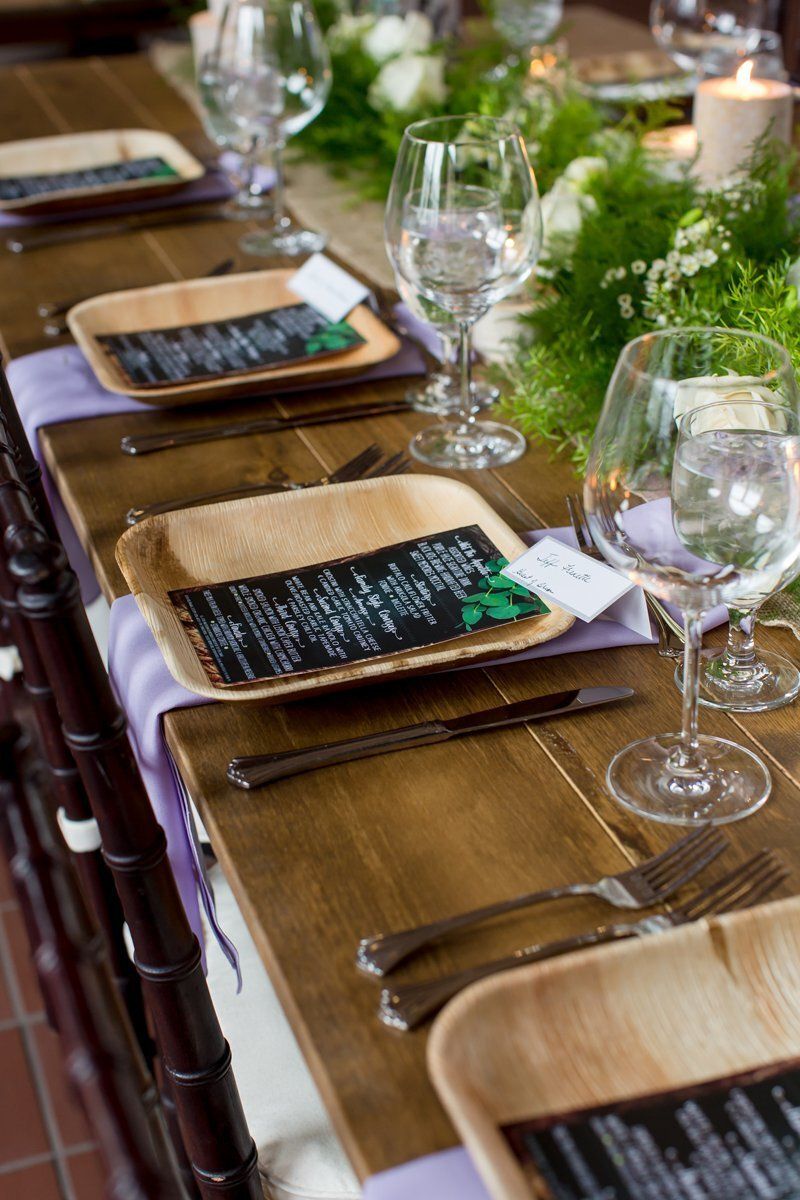 Set dining table with tan placemats, black napkins, wine glasses, and silverware