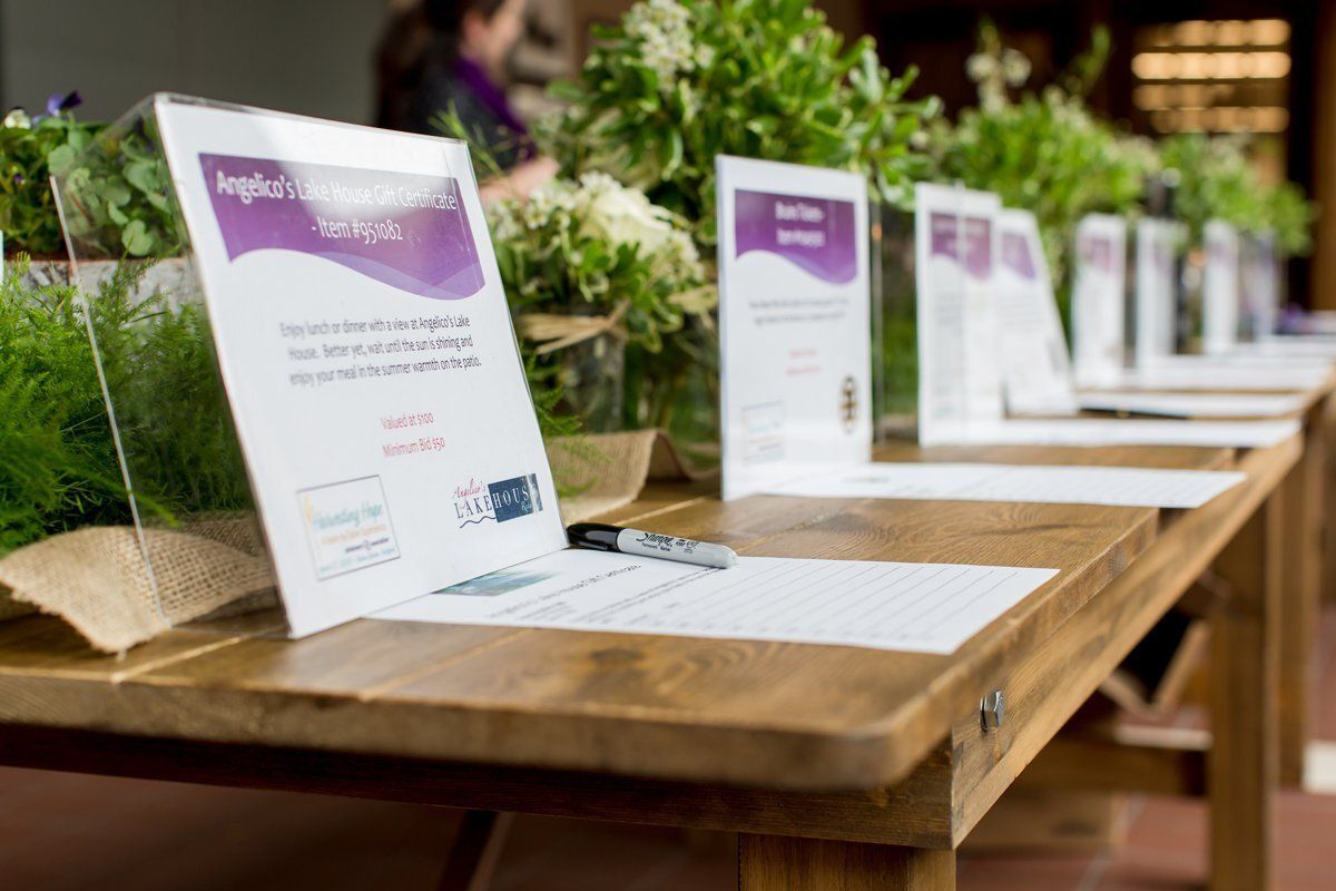 Row of purple-and-white display signs on a long wooden table at an indoor event.