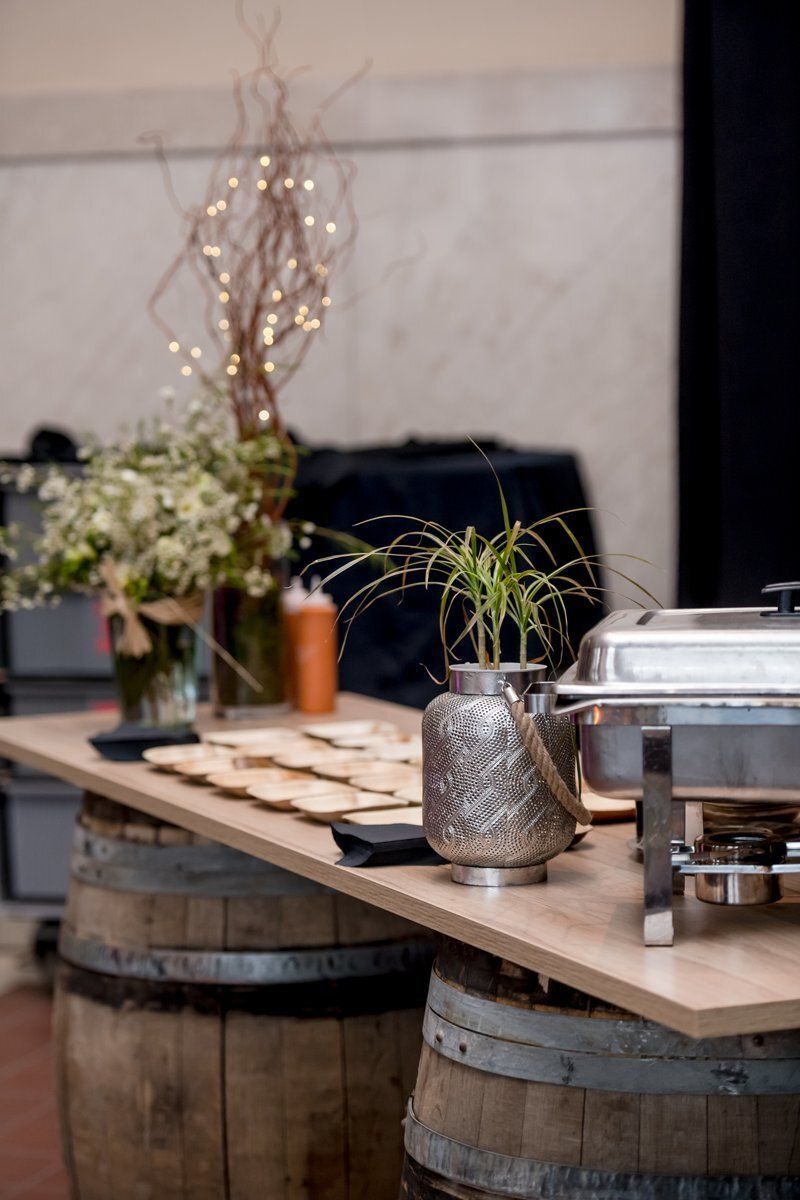 Wooden table on barrels with potted plants and a floral arrangement in a rustic indoor setting