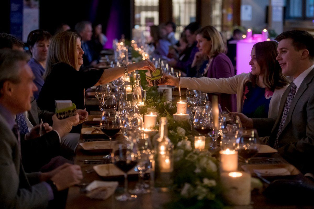 Guests dining at a candlelit banquet table in a dimly lit event hall