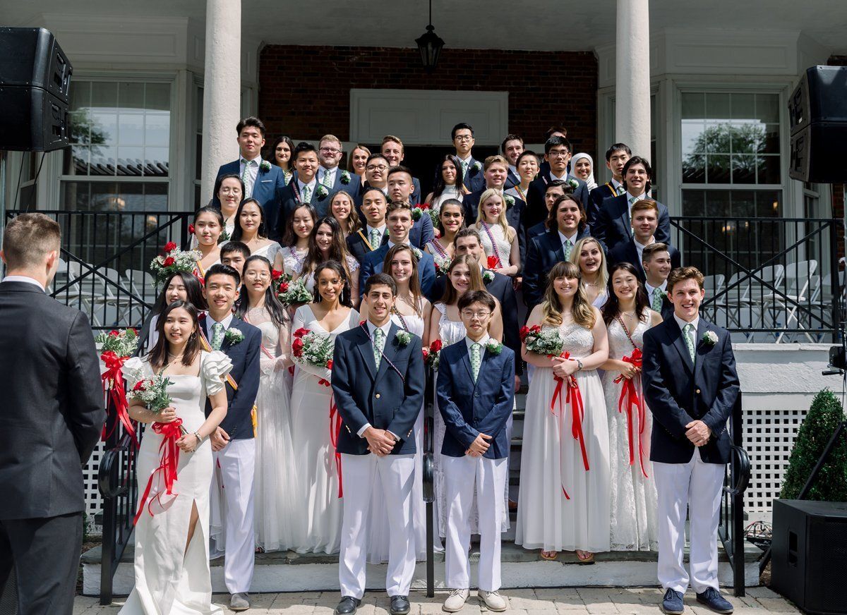 Large wedding party posing on church steps, with bride and groom in front and guests behind them