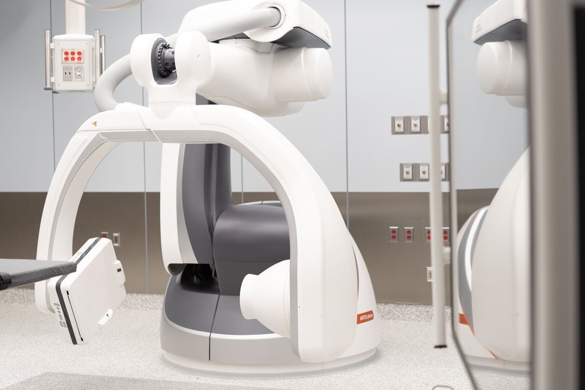 White medical robot in a clinic room with a curved frame and attached arm