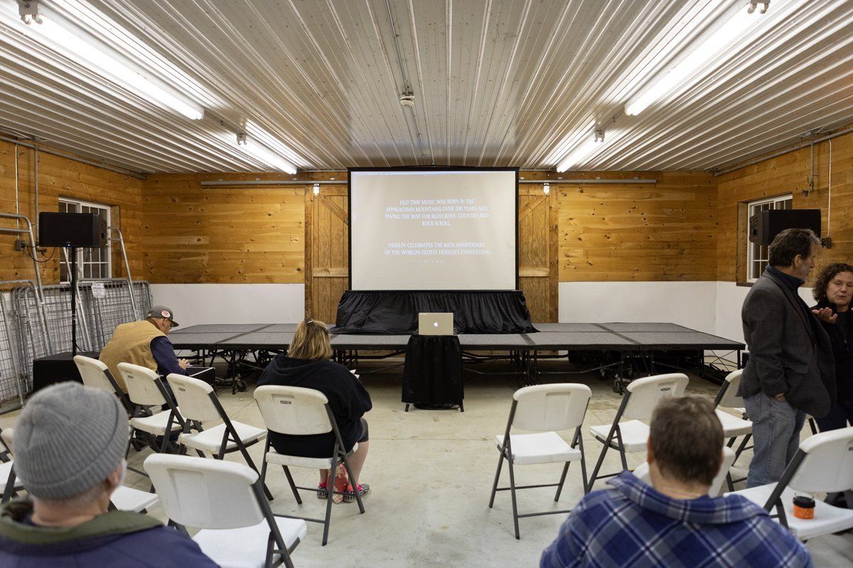 Small hall with projector screen, rows of folding chairs, and a few people waiting inside.