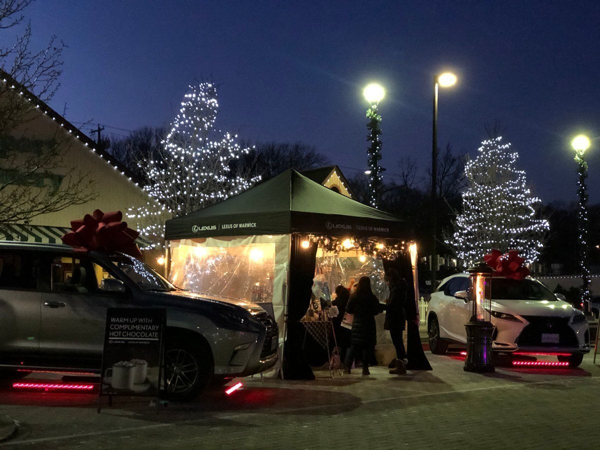 Holiday market tents and decorated trucks lit up at night under string lights