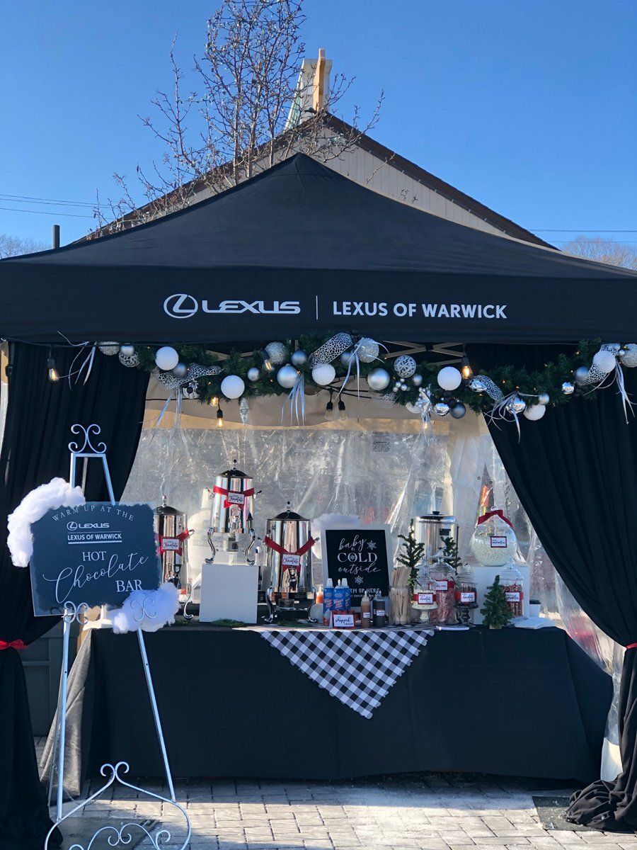 Holiday display under black Lexus Warwick tent with decorated tables and white ornaments
