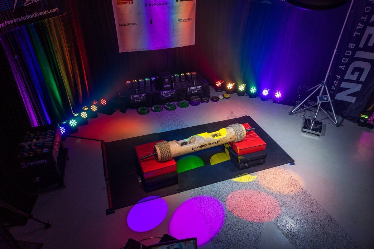 Colorful stage with rainbow lights, low platform, and two bright circular rugs in a dark event space