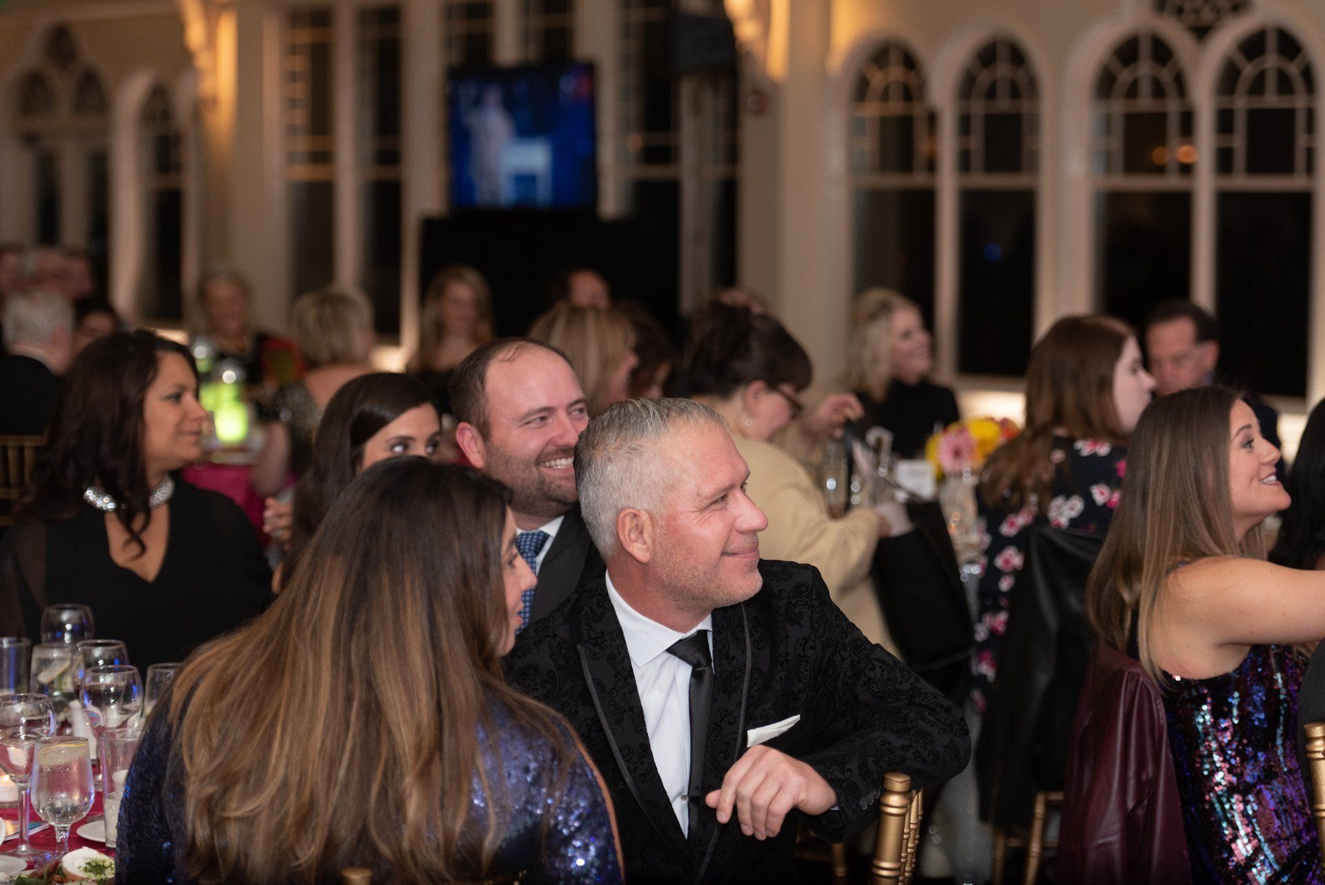 Guests seated at a formal event, chatting at round tables in a banquet hall