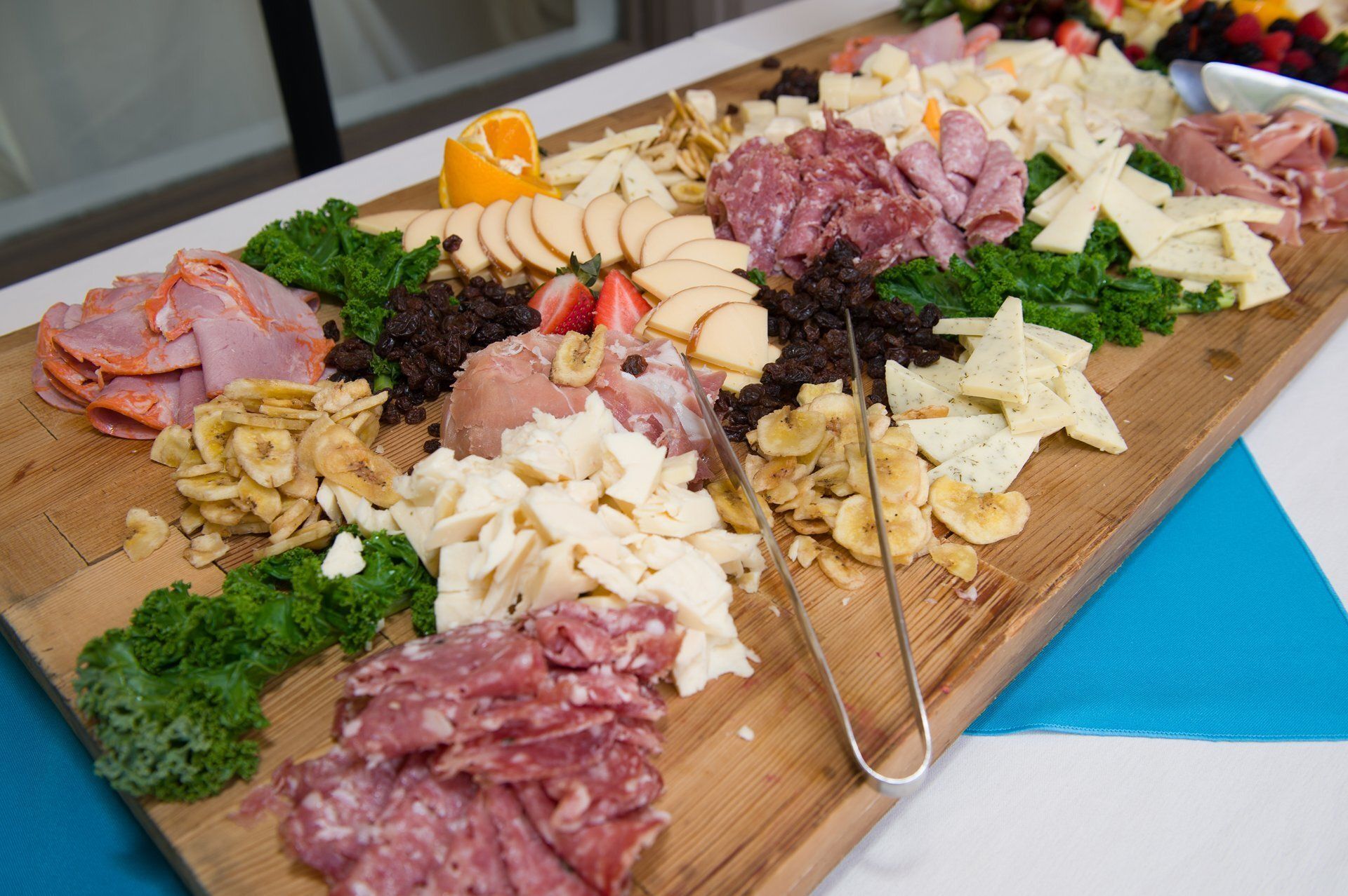 Charcuterie board with assorted meats, cheeses, crackers, nuts, and parsley on a wooden platter