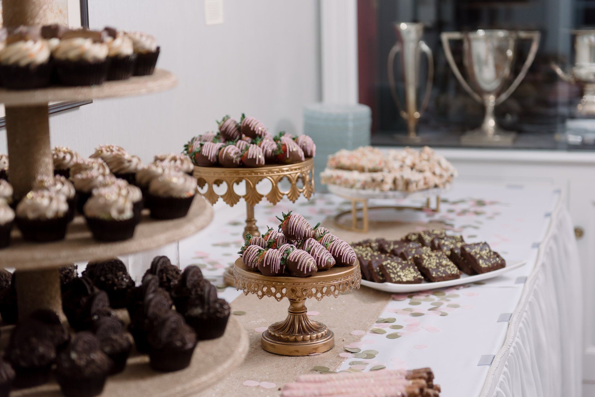Dessert buffet table with assorted pastries on gold stands and platters in a banquet setting
