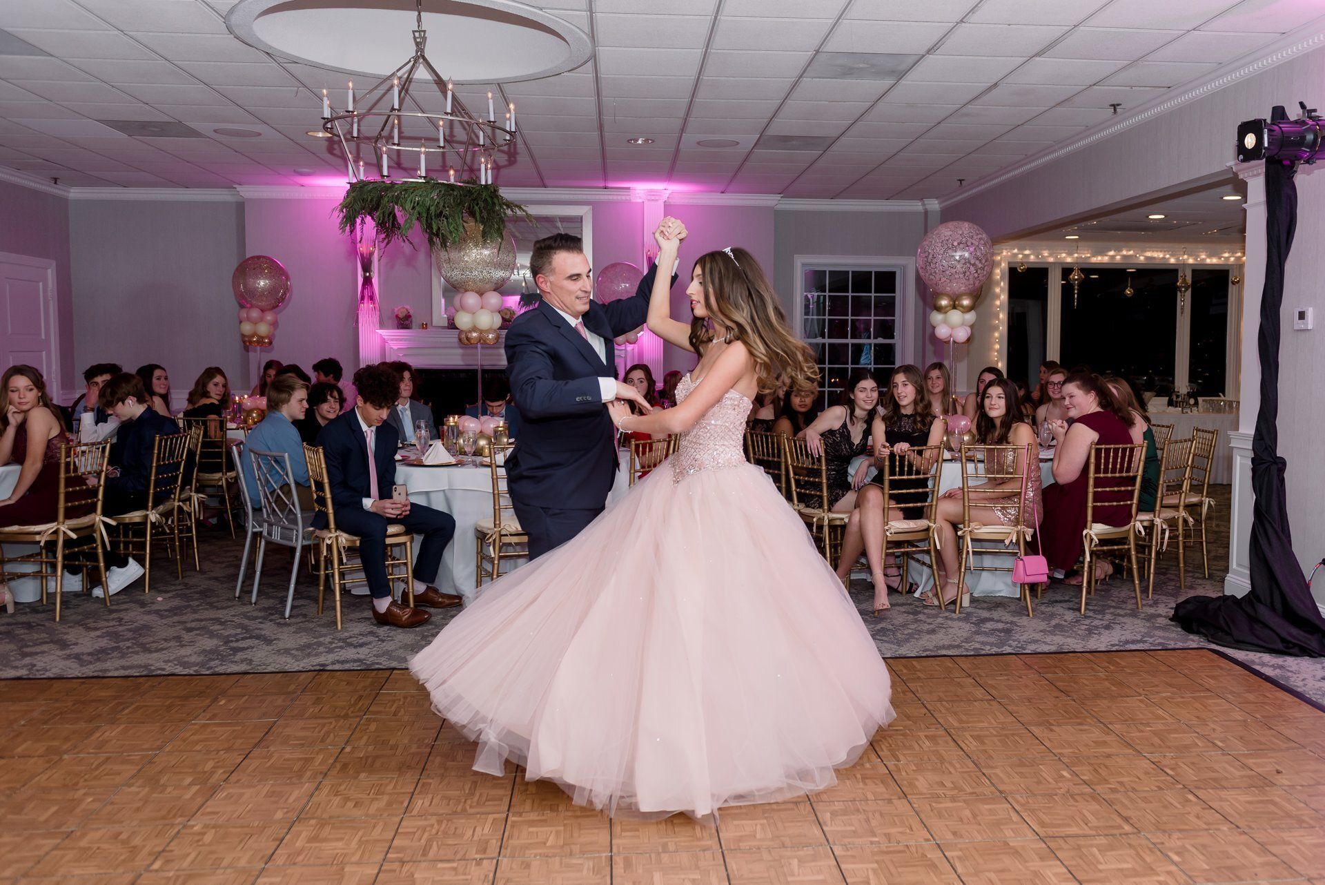 Bride and groom dancing at a wedding reception in a pink-lit banquet hall