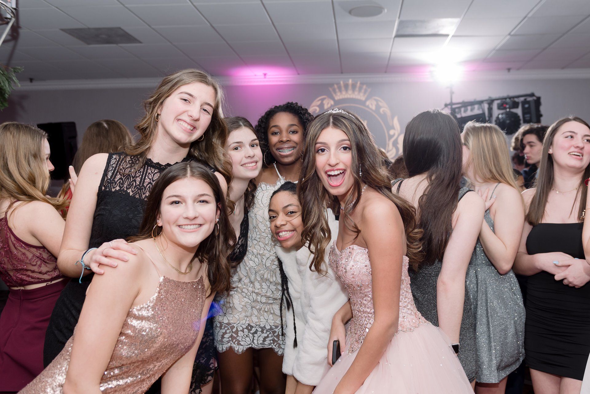 A group of people smiling and posing together at a party under pink lighting