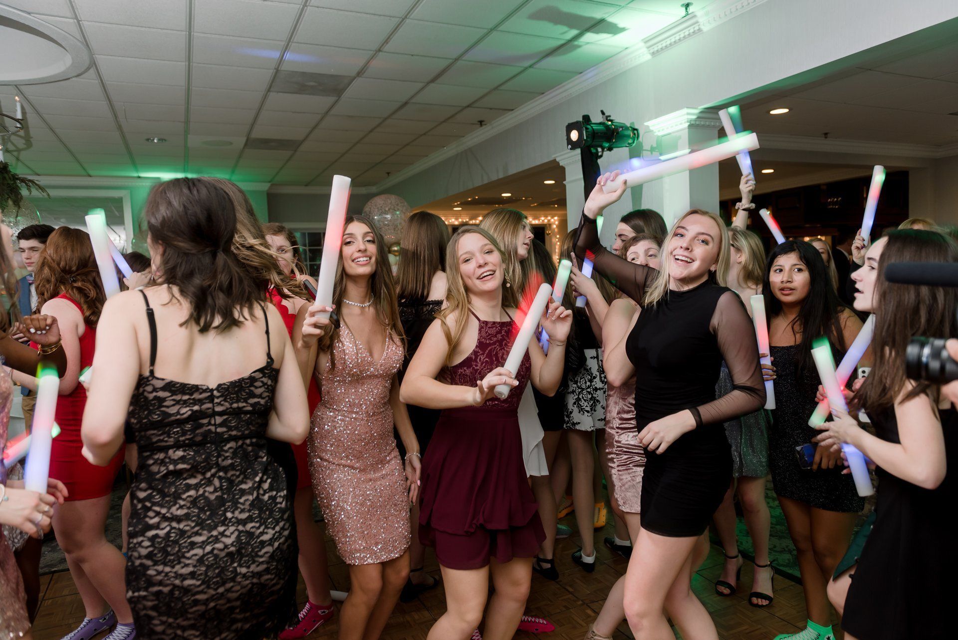 Group of people dancing and holding glow sticks at a lively indoor party