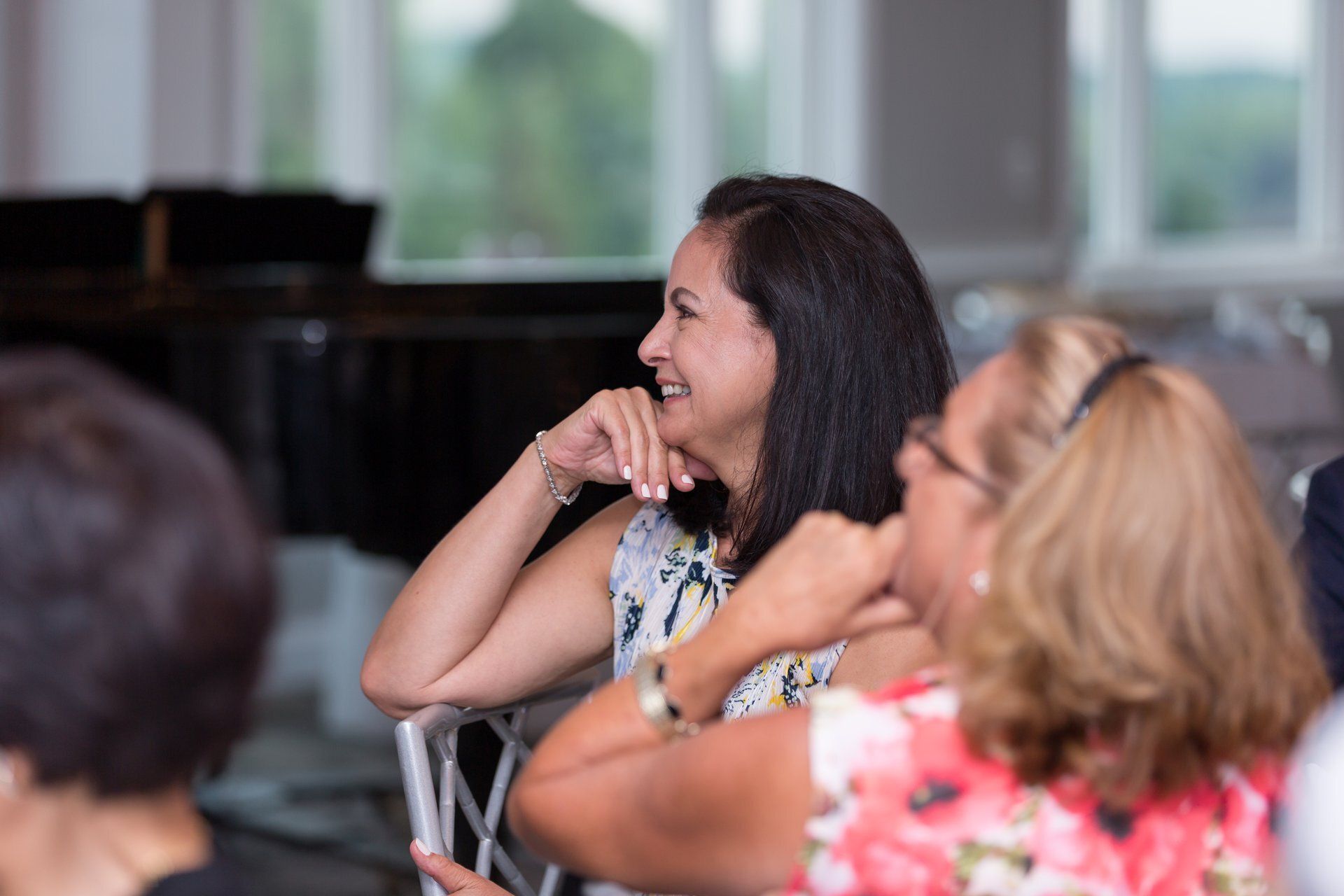 Audience seated in a bright room, smiling and listening attentively