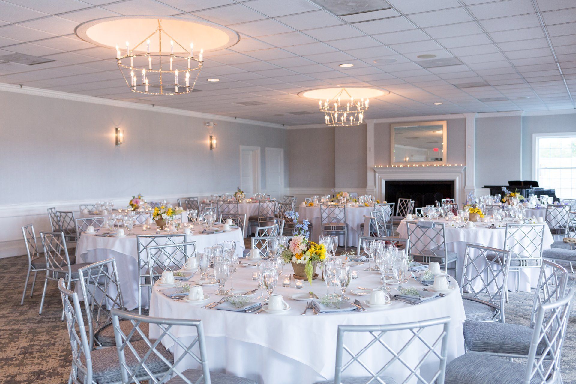 Elegant banquet hall with round tables, white linens, and silver chairs under chandeliers