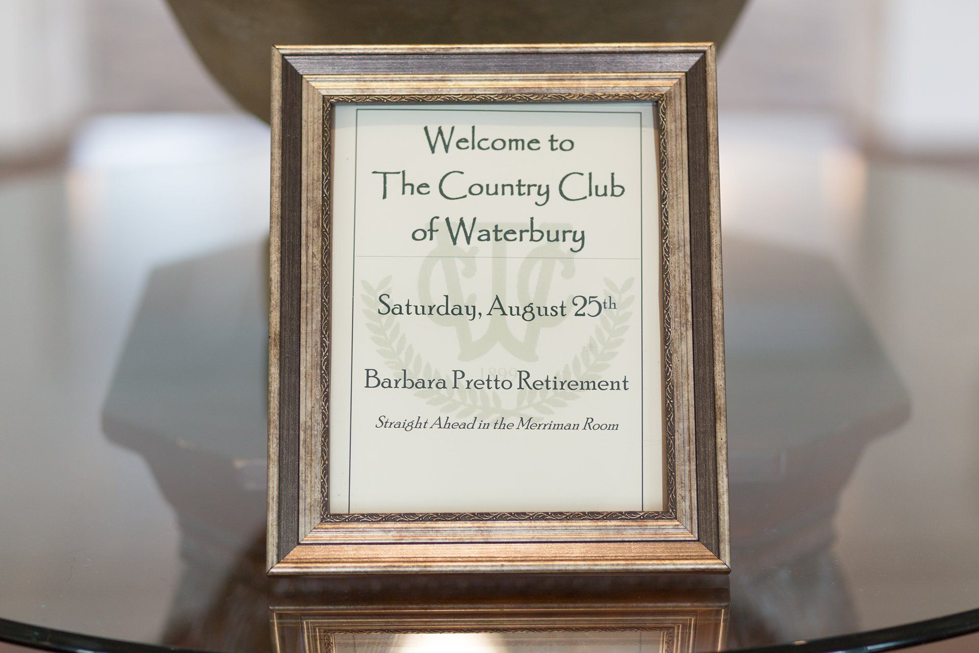 Framed wedding welcome sign on a reflective table, reading “Welcome to The Country Club of Waterbury.”