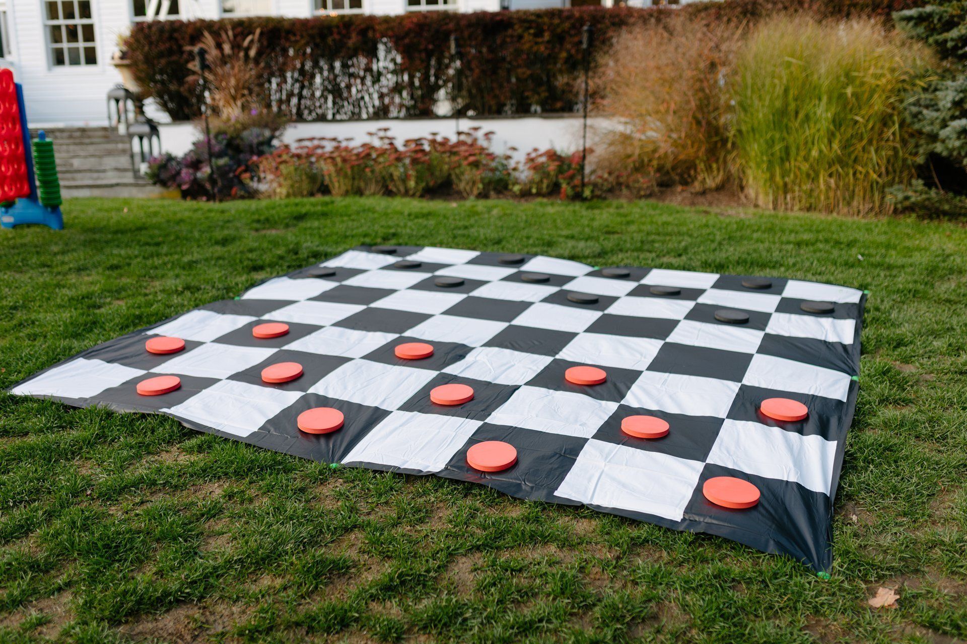 Outdoor oversized checkers board on grass with red and black pieces