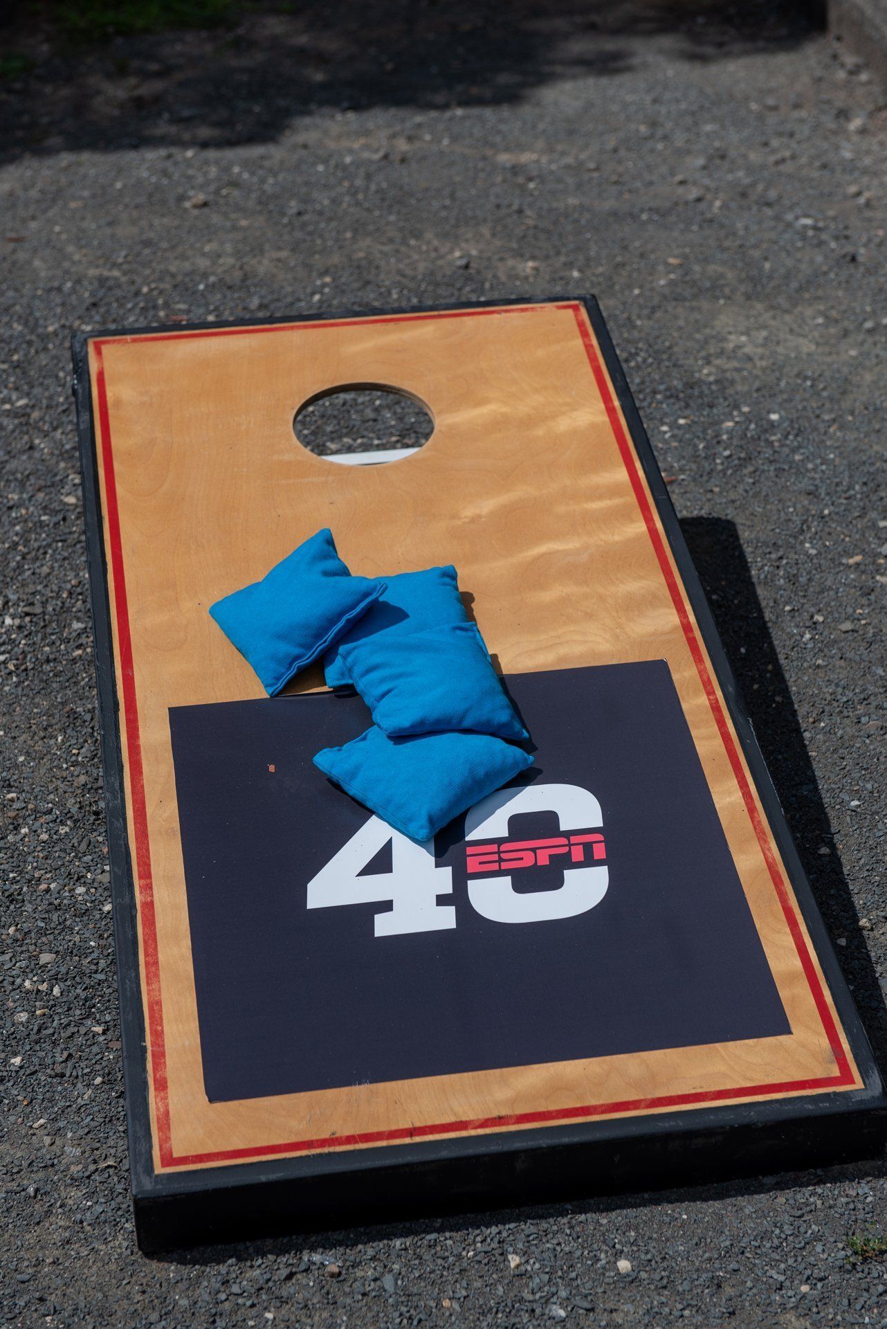 Cornhole board with blue bean bags on a black and tan surface, marked with a 48 ESPN logo.