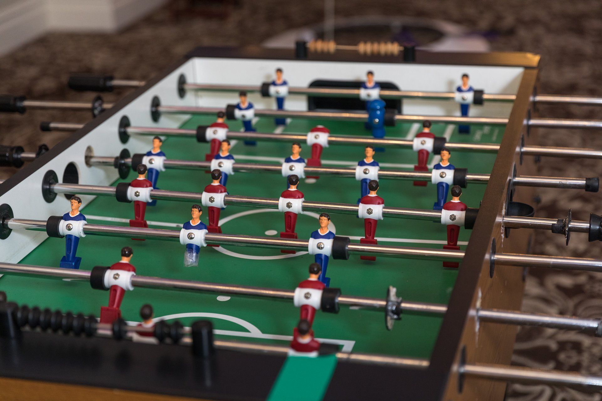 Foosball table with red and blue players on a green field, viewed from above