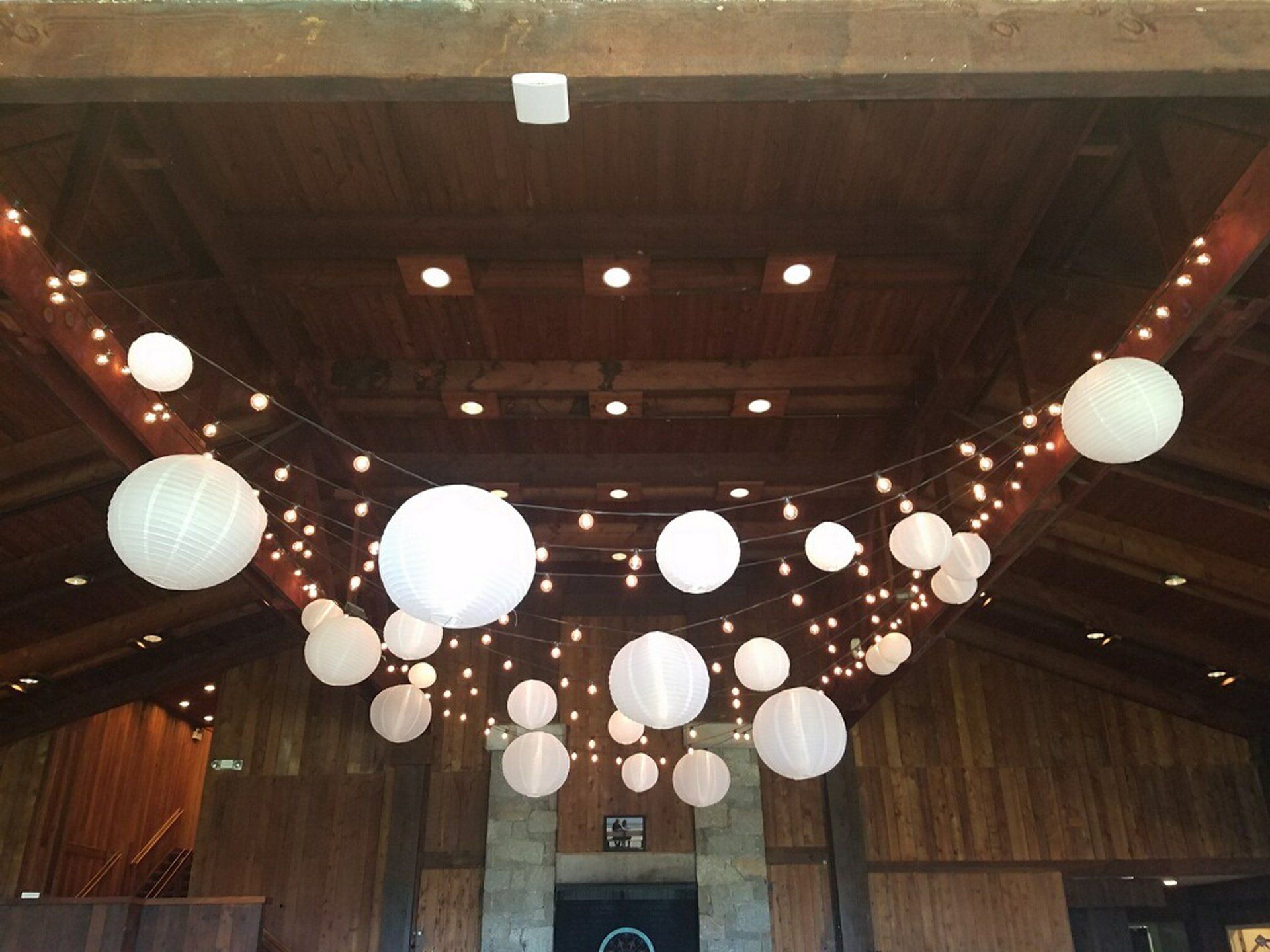 Wooden hall ceiling with hanging white lanterns and string lights, creating a warm decorative ambiance