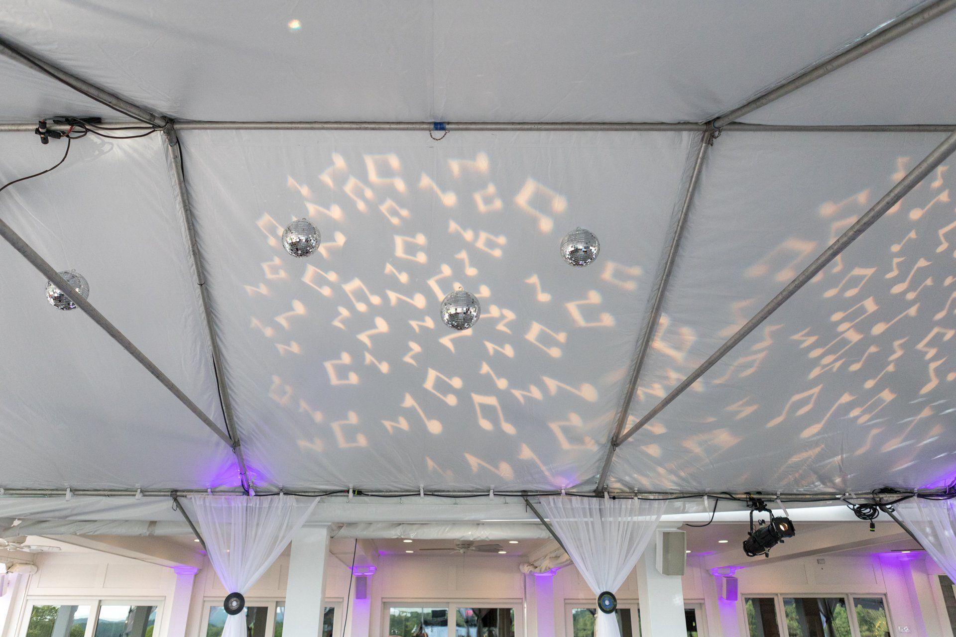 White event tent ceiling with purple uplighting and patterned light reflections on the fabric