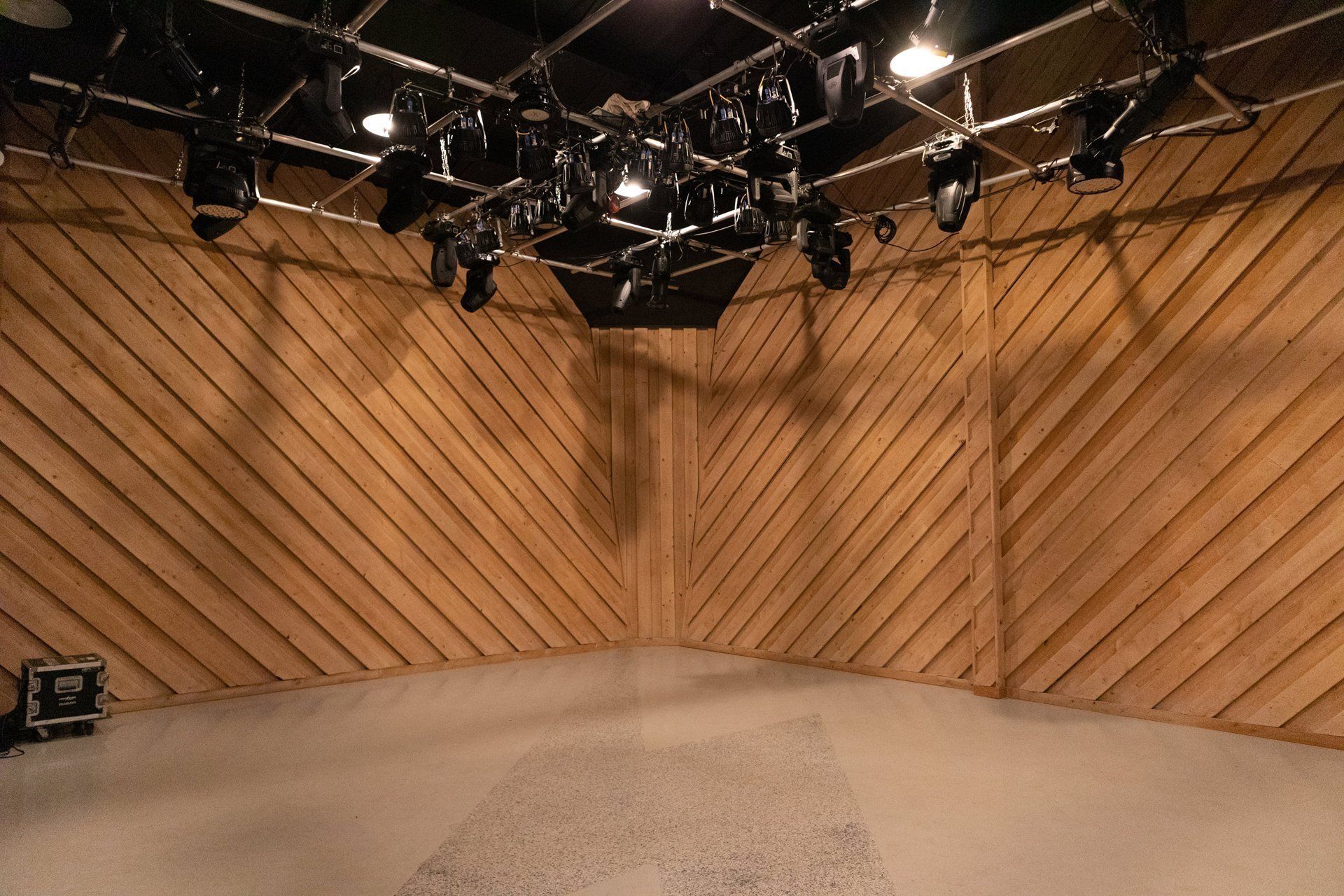 Empty studio set with wood-paneled walls and overhead stage lights