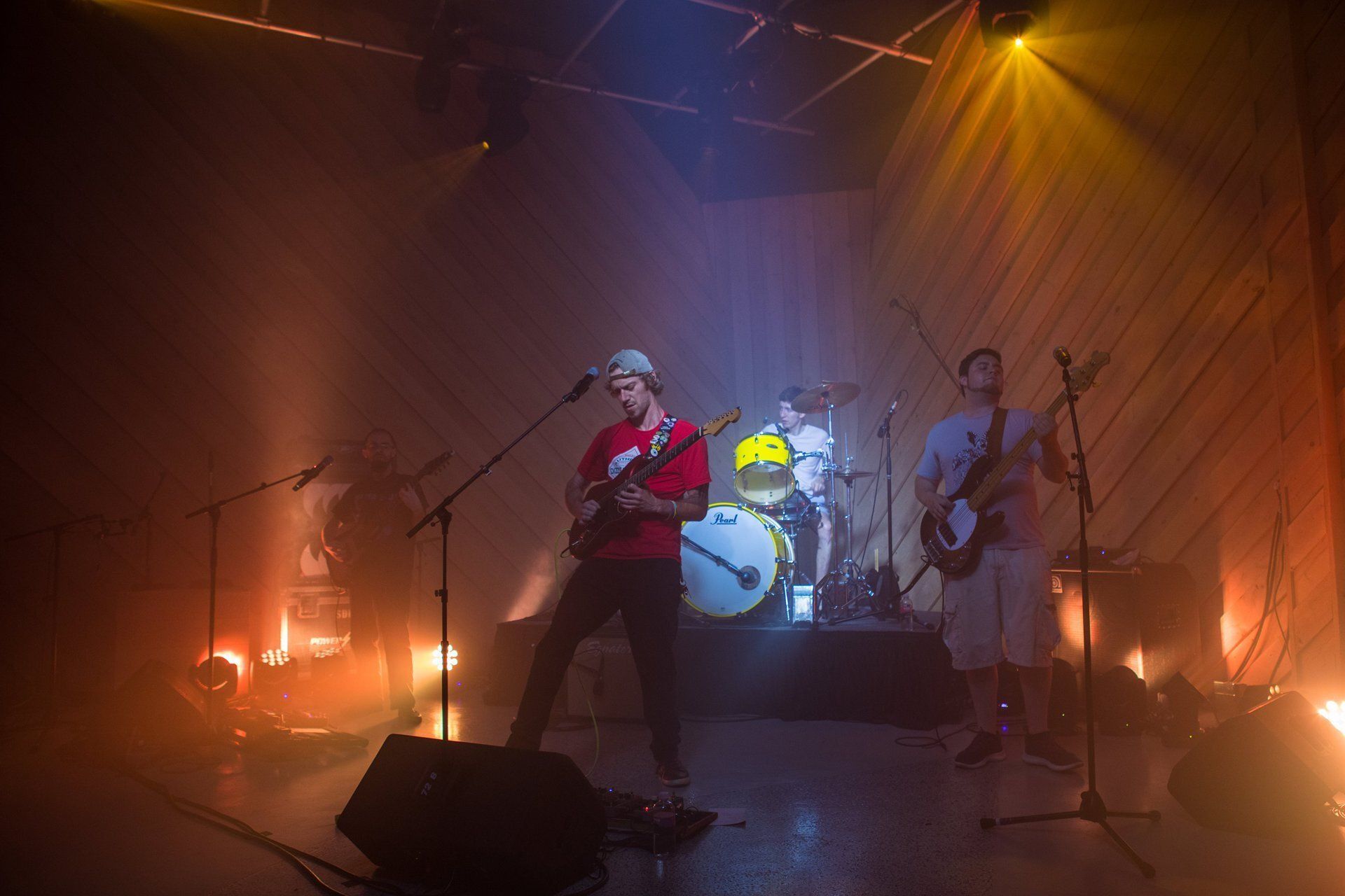 Live band performing on a smoky stage under warm orange and yellow lights