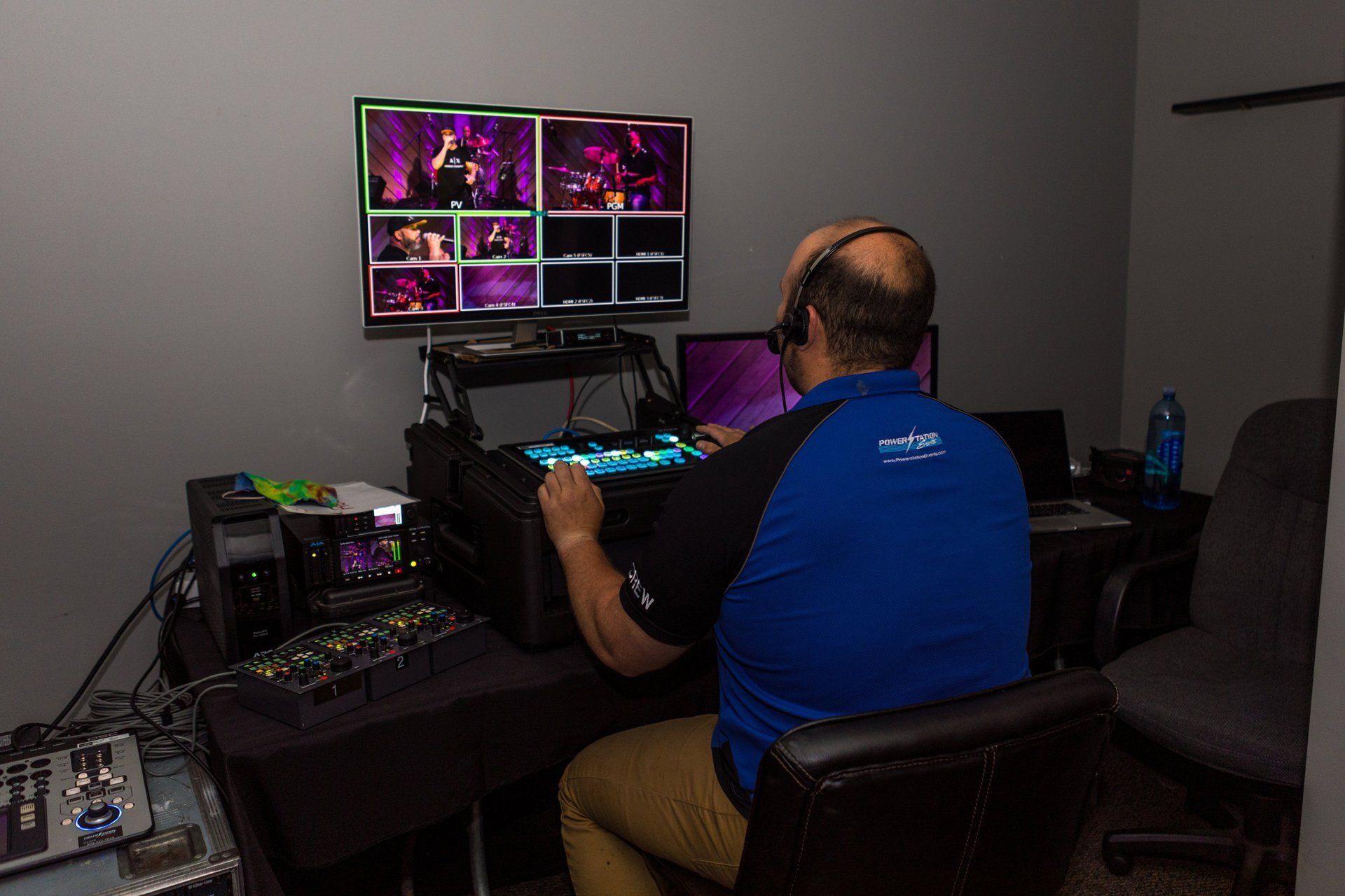 Person at a desk using a computer with multiple colorful monitors in a dim room