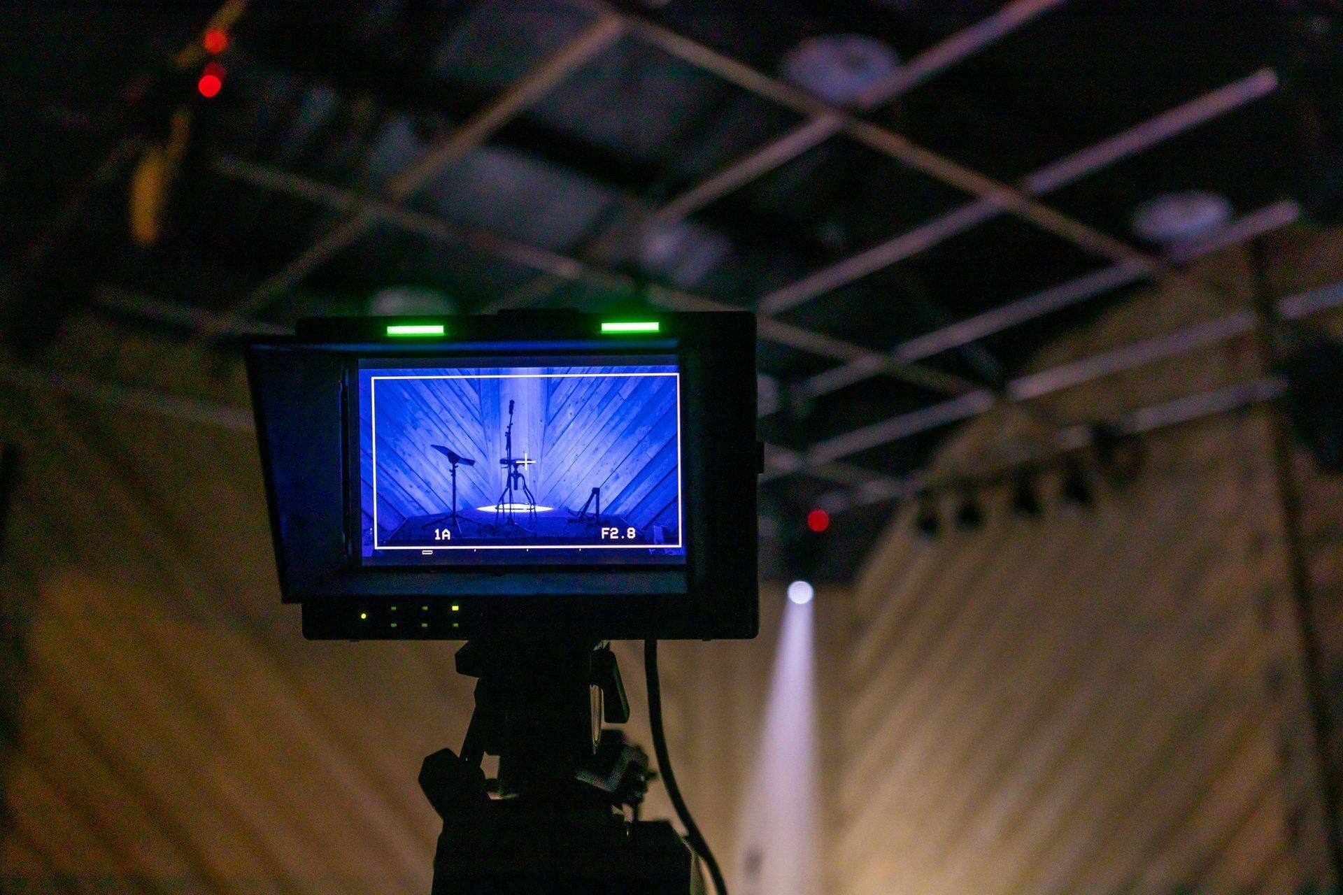 Camera monitor showing a blue-lit stage with a person silhouette and spotlight in a dark studio