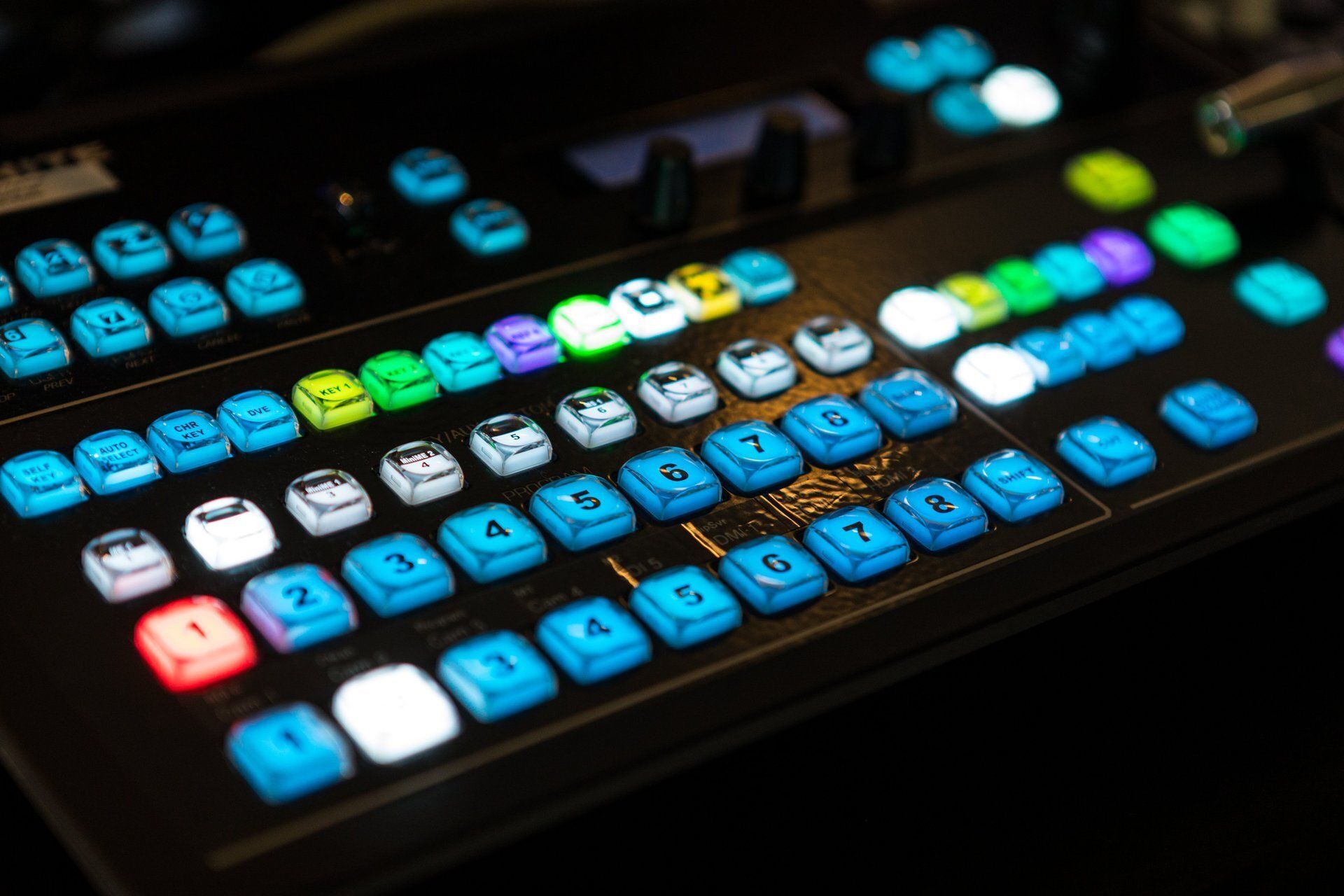 Colorful illuminated keyboard with blue, white, and neon keys on a dark surface