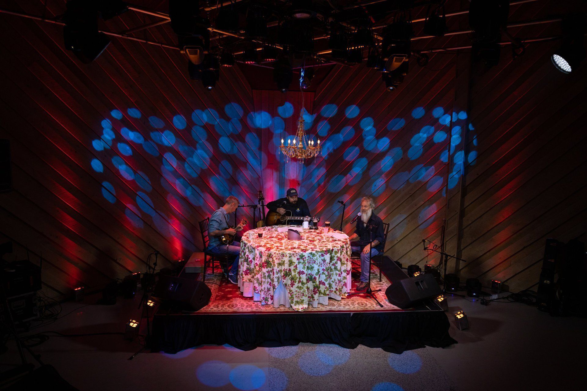 DJ performing on a small stage with colorful blue and red light patterns in a dark room
